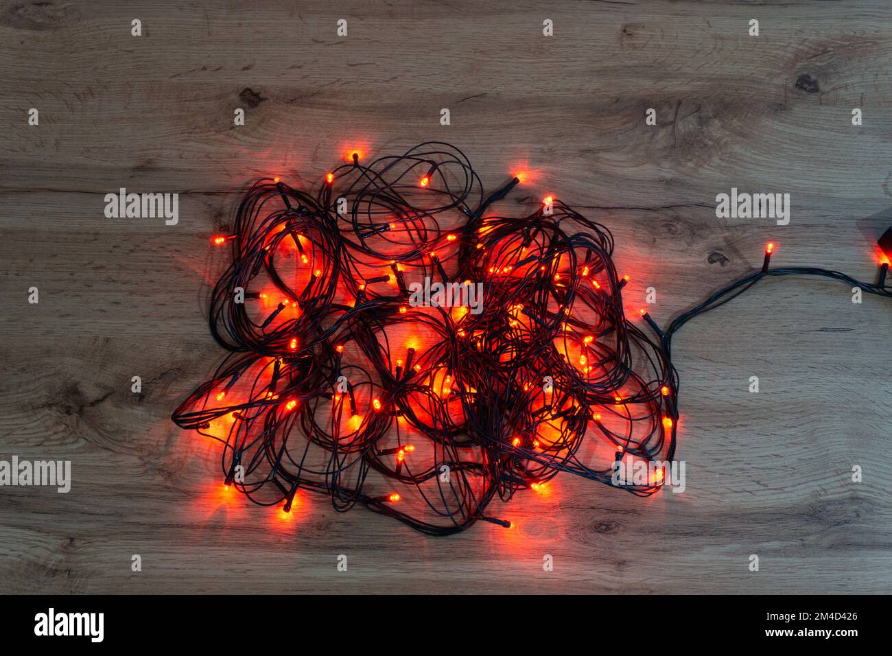 luci rosse di natale aggrovigliate su un tavolo di legno Foto Stock