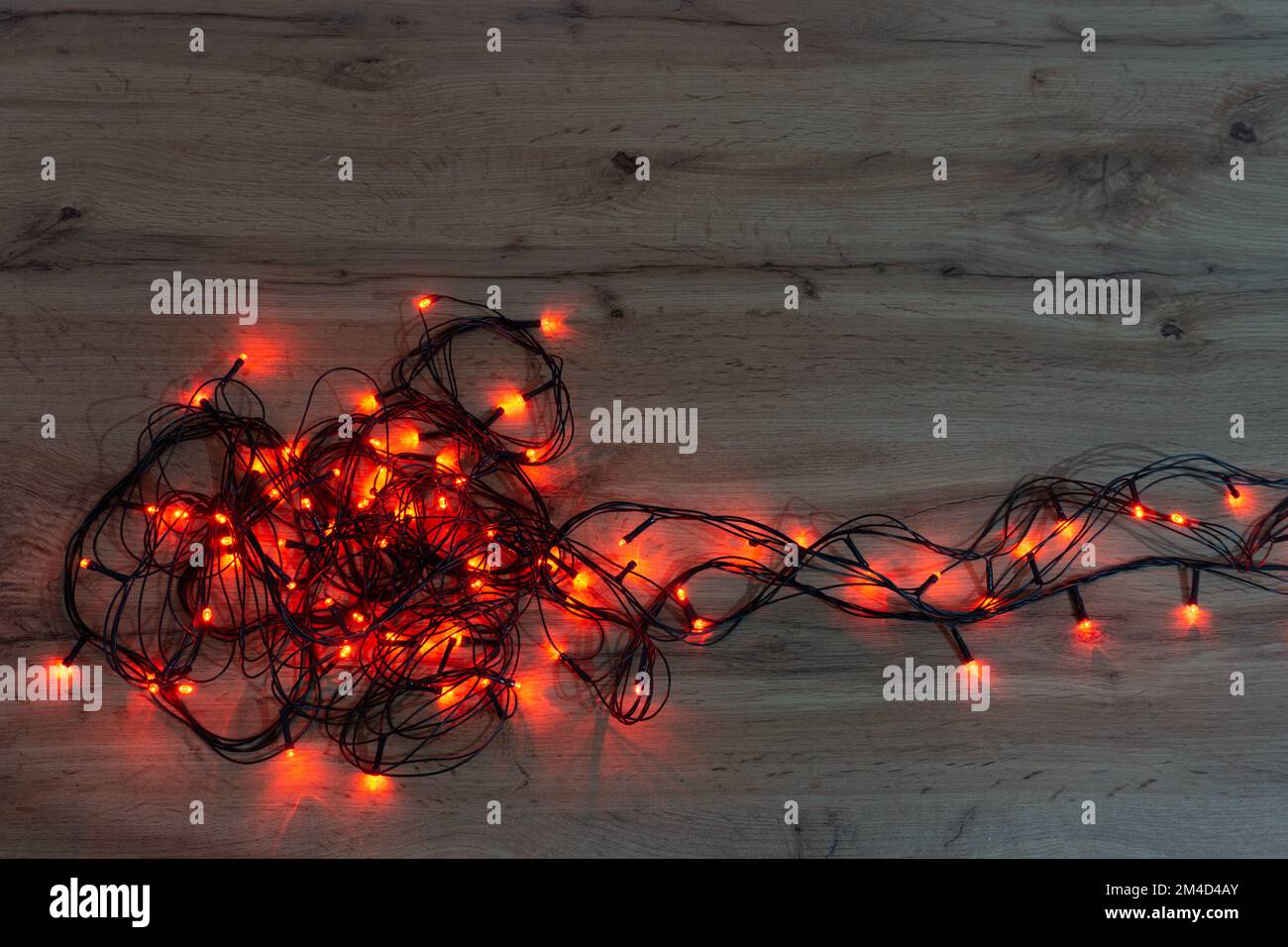 luci rosse di natale aggrovigliate su un tavolo di legno Foto Stock