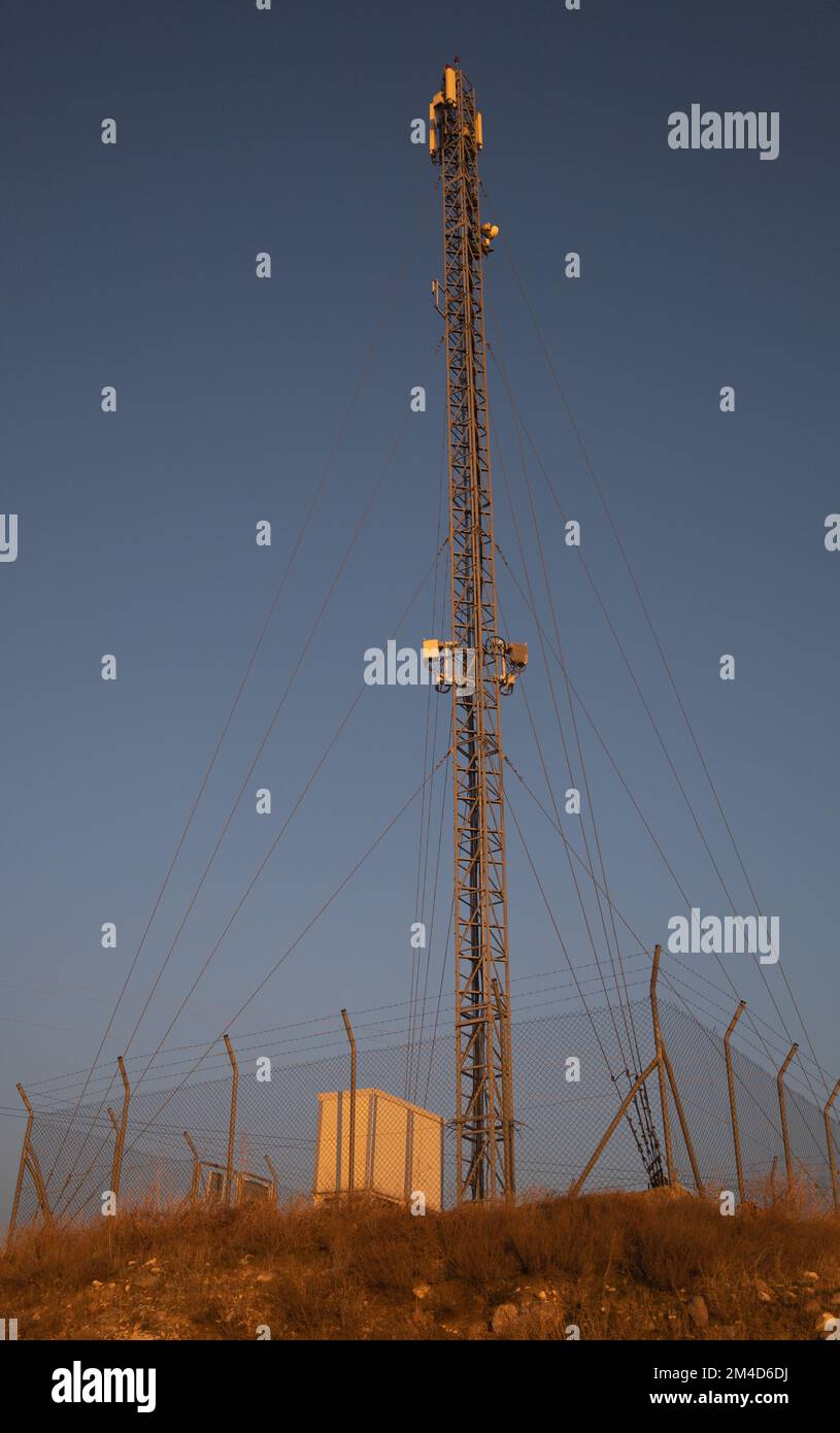 Torre delle cellule isolata circondata da recinzione di filo spinato Foto Stock