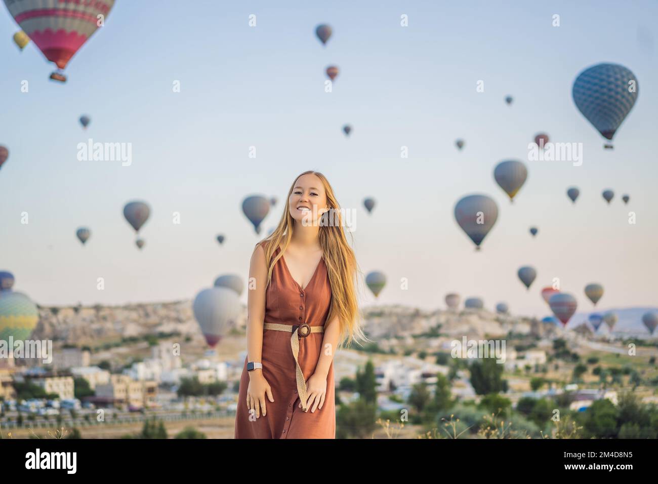 Donna turistica che guarda mongolfiere in Cappadocia, Turchia. Buon viaggio in Turchia concetto. Donna in cima a una montagna che gode di una vista meravigliosa Foto Stock