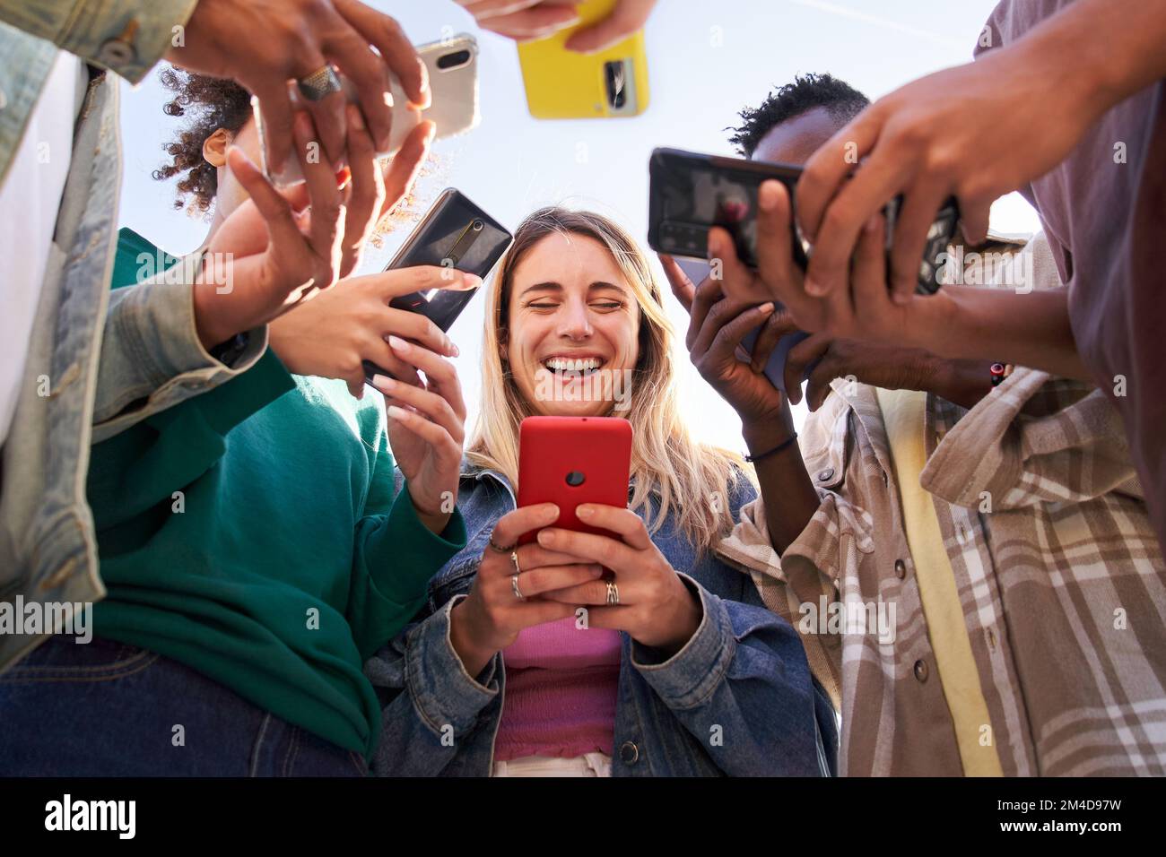 Vista ad angolo basso di un gruppo di giovani adolescenti che utilizzano telefoni cellulari. Concetto di tecnologia, connessione. Foto Stock