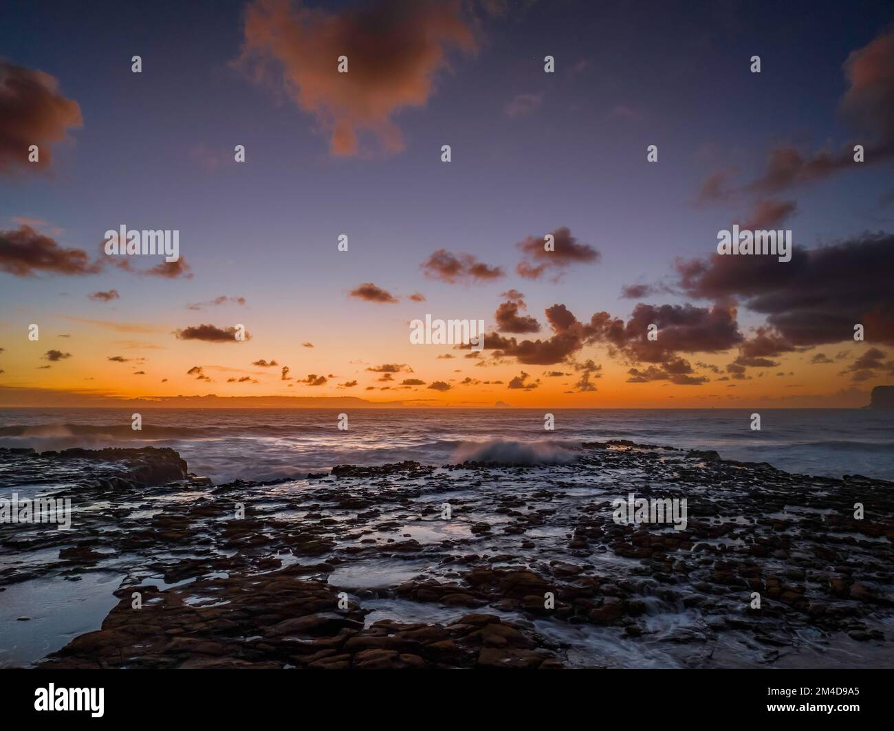 Dawn Seascape con nuvole, piattaforma rocciosa, onde di buone dimensioni e molta atmosfera a North Avoca Beach sulla costa centrale, NSW, Australia. Foto Stock
