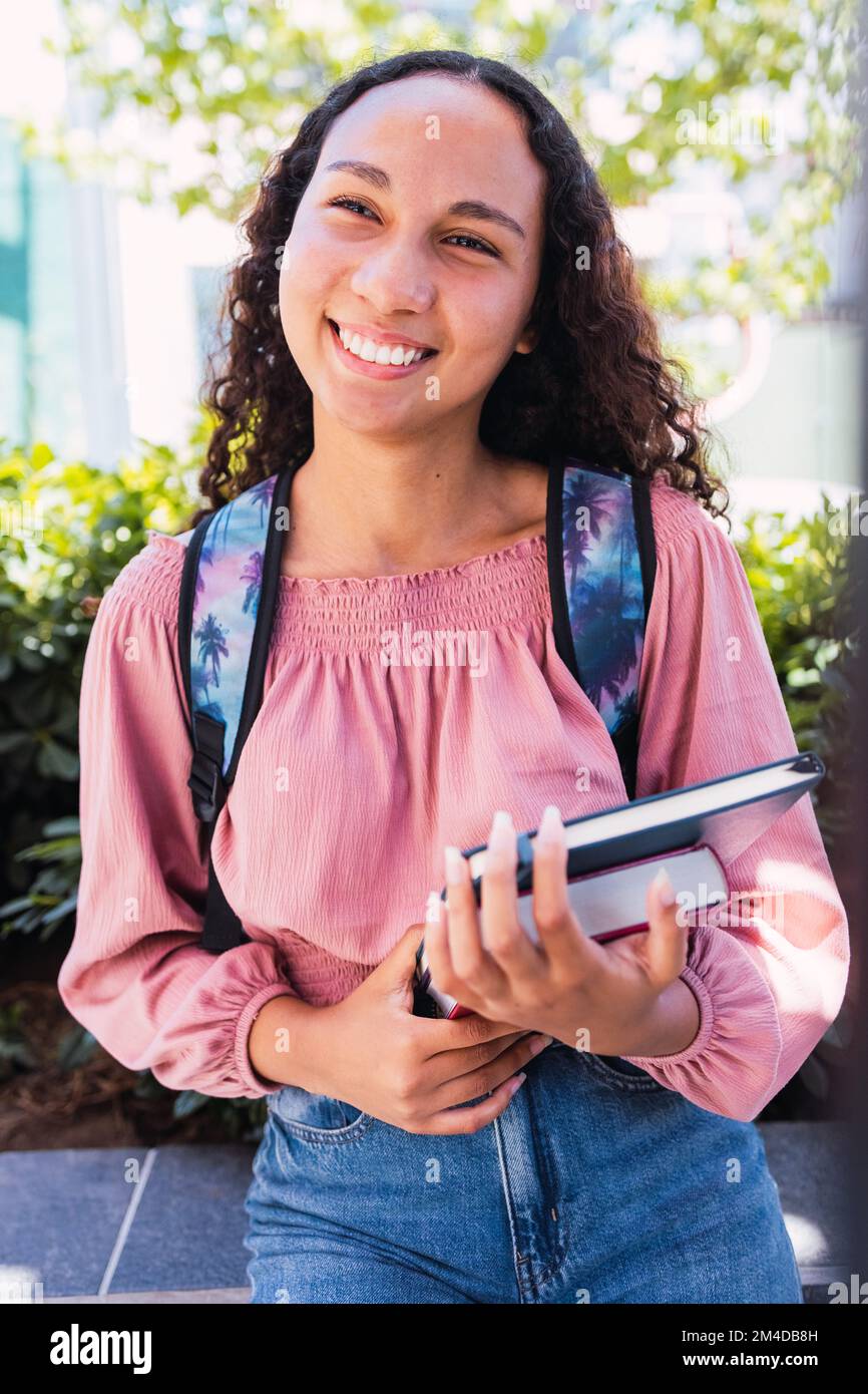 Primo piano felice giovane studentessa latina che tiene i suoi libri fuori dal campus. Concetto di istruzione Foto Stock