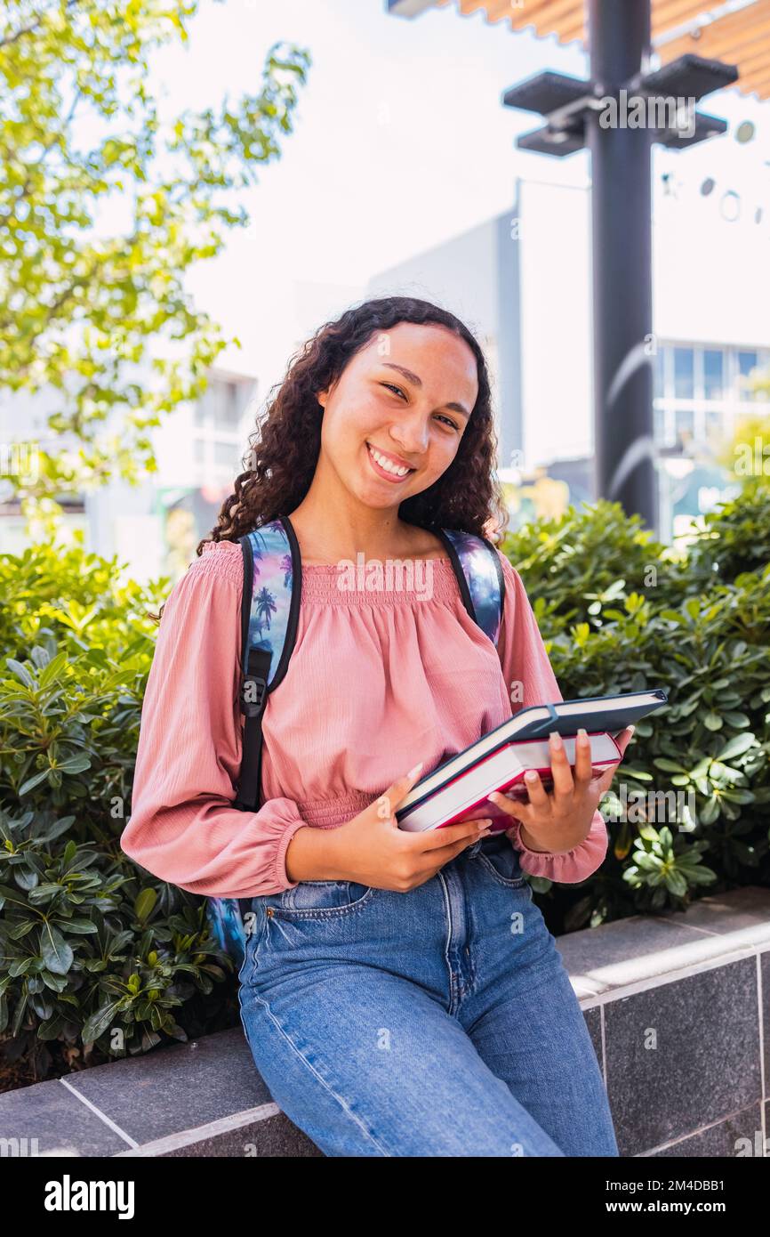 Primo piano felice giovane studentessa latina che tiene i suoi libri fuori dal campus. Concetto di istruzione Foto Stock