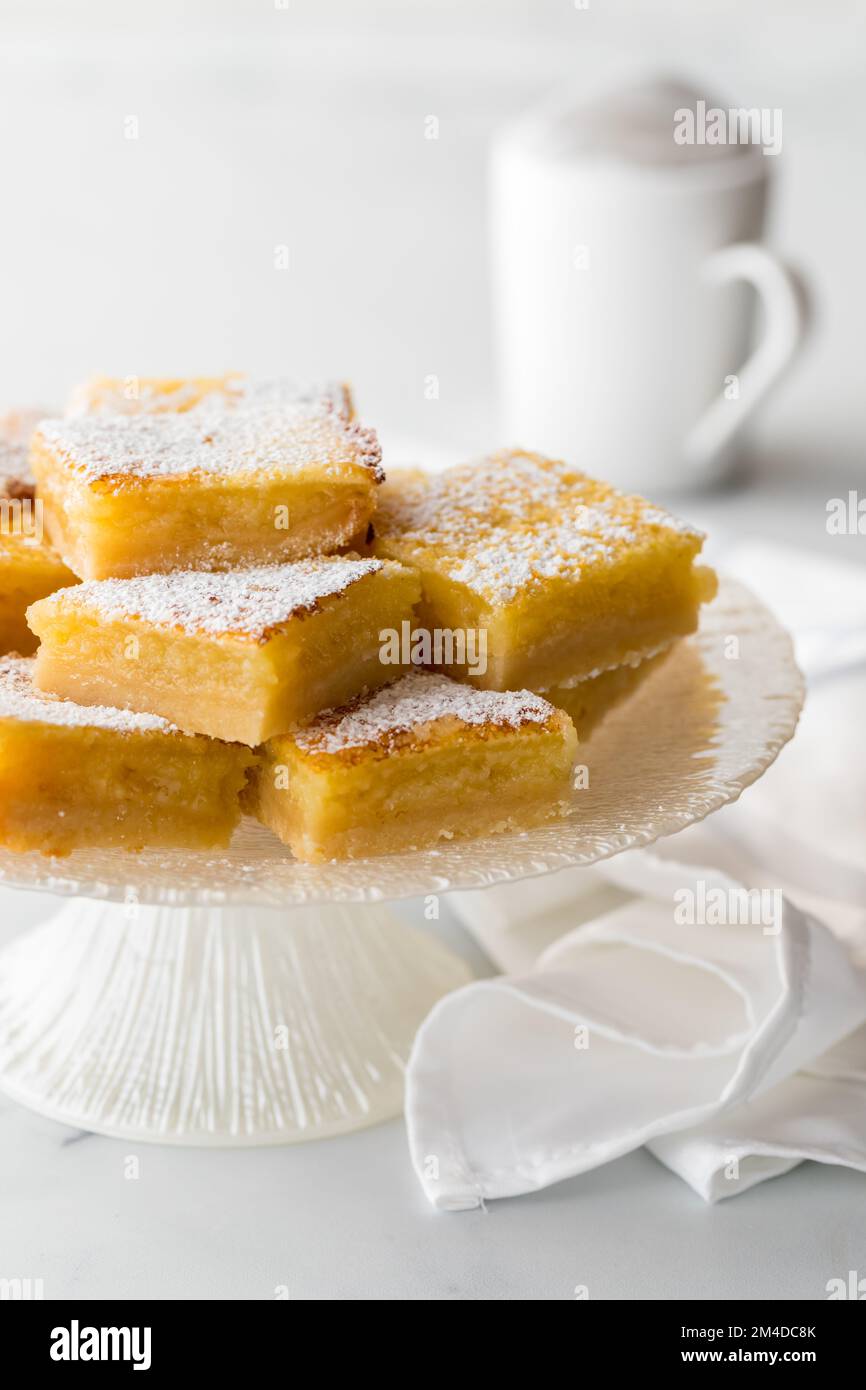 Quadrati di limone dolce fatti in casa su un piedistallo cosparso di zucchero a velo. Foto Stock