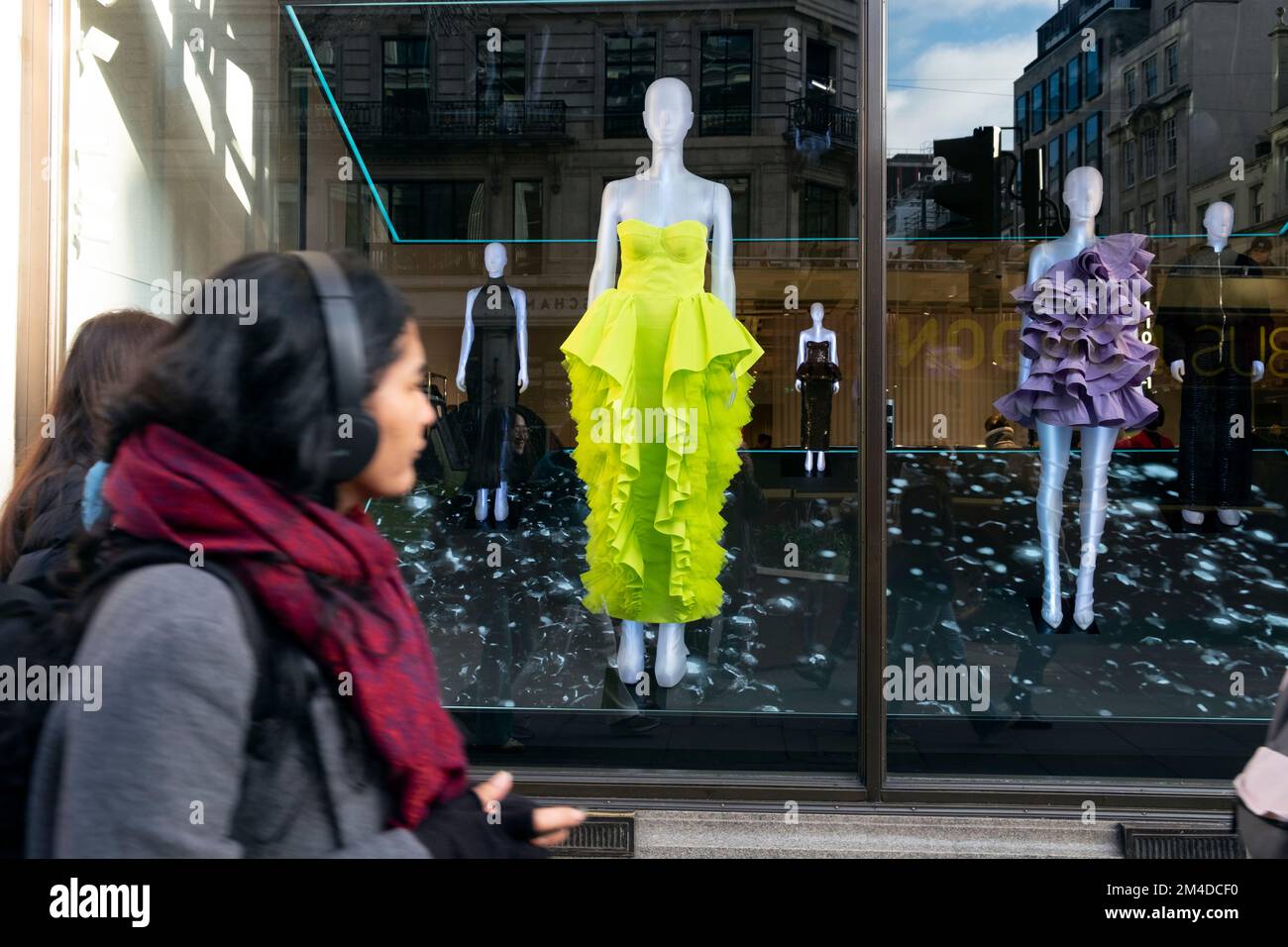 Giovane donna shopper guardando il vestito verde lime nella finestra del negozio H&M su Regent Street Christmas Dicembre 2022 West End Londra Inghilterra UK KATHY DEWITT Foto Stock