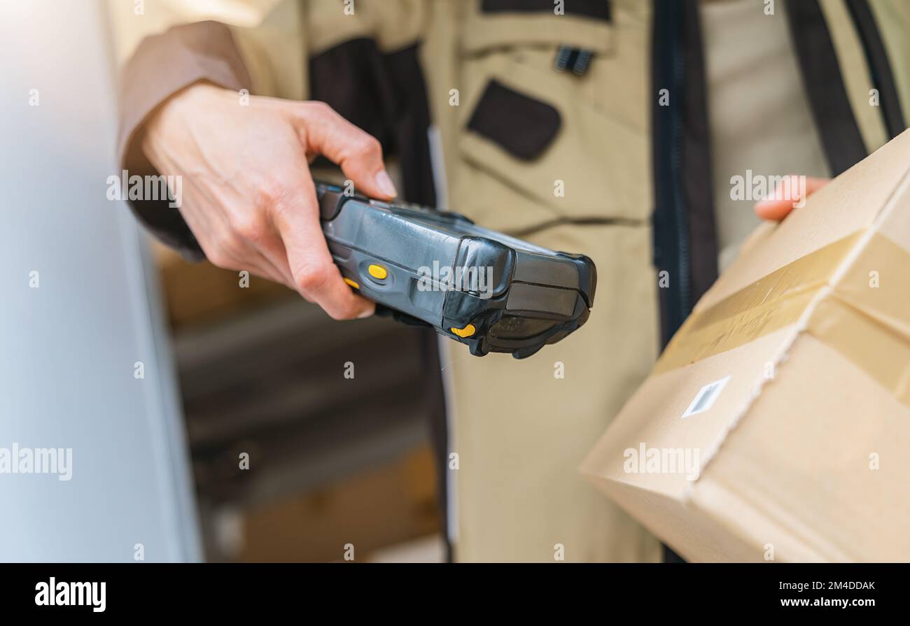 l'agente di consegna esegue la scansione del codice a barre con il lettore di codici a barre su un pacco durante il turno di lavoro. Immagine del concetto di consegna del corriere Foto Stock