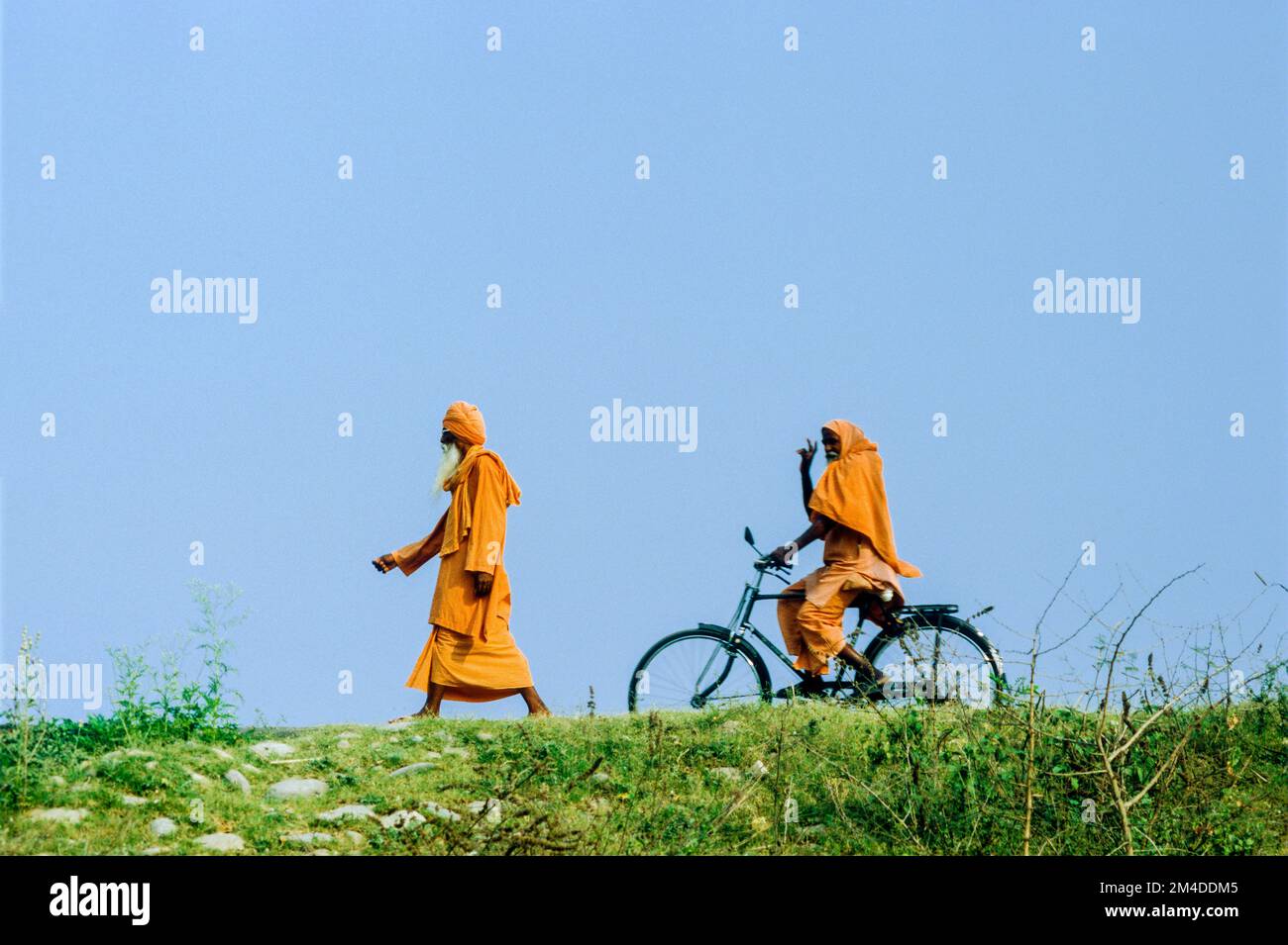 Due Sadhus, uomini santi, pedalando e tornando al loro ashram vicino ad Haridwar. Haridwar , India Foto Stock
