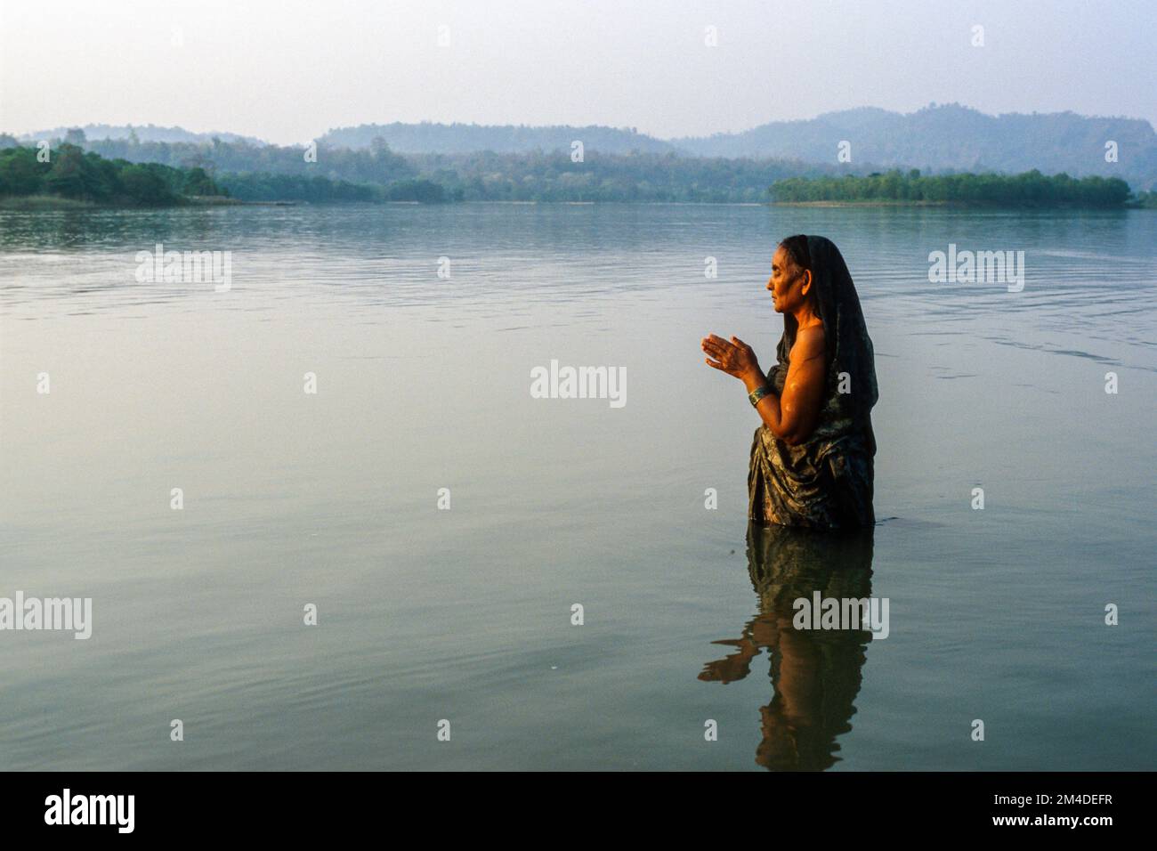 Donna che prega a Dio nell'acqua fredda e limpida del fiume Gange Foto Stock