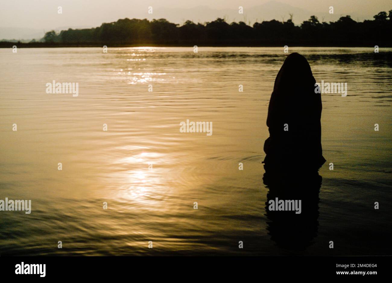 Donna che prega a Dio nell'acqua fredda e limpida del fiume Gange Foto Stock