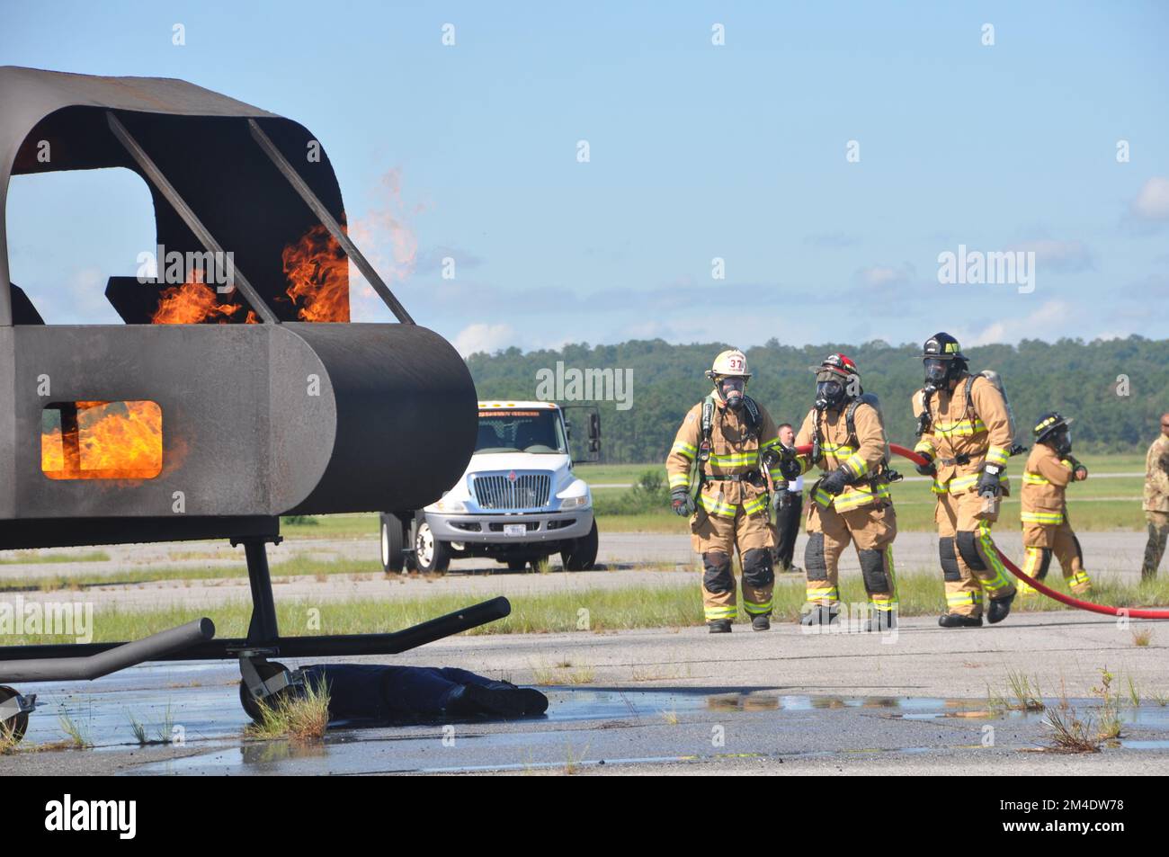 Vigili del fuoco del 908th Airlift Wing 908th Civil Engineer Squadron avvicinarsi a un incendio in elicottero come vigili del fuoco del Fort Benning Vigili del fuoco guardare durante un esercizio di addestramento che coinvolge un elicottero aereo addestratore di fuoco 4 agosto 2022, a Fort Benning Georgia. I vigili del fuoco 908th hanno collaborato con il Dipartimento dei vigili del fuoco di Fort Benning per condurre la loro prima formazione congiunta sull'interoperabilità e per utilizzare l'addestratore di elicotteri per accelerare il loro addestramento in preparazione alla remissione 908 AW all'unità di addestramento formale dell'aeronautica militare per l'elicottero MH-139A Grey Wolf. (STATI UNITI Air Forc Foto Stock