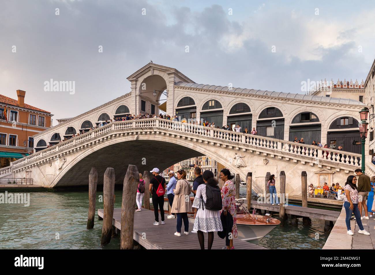 La vista sul Ponte di Rialto sul Canal Grande a Venezia. I turisti soggiornano sul Ponte di Rialto e guardano le gondole e le barche sul Canal Grande. Foto Stock