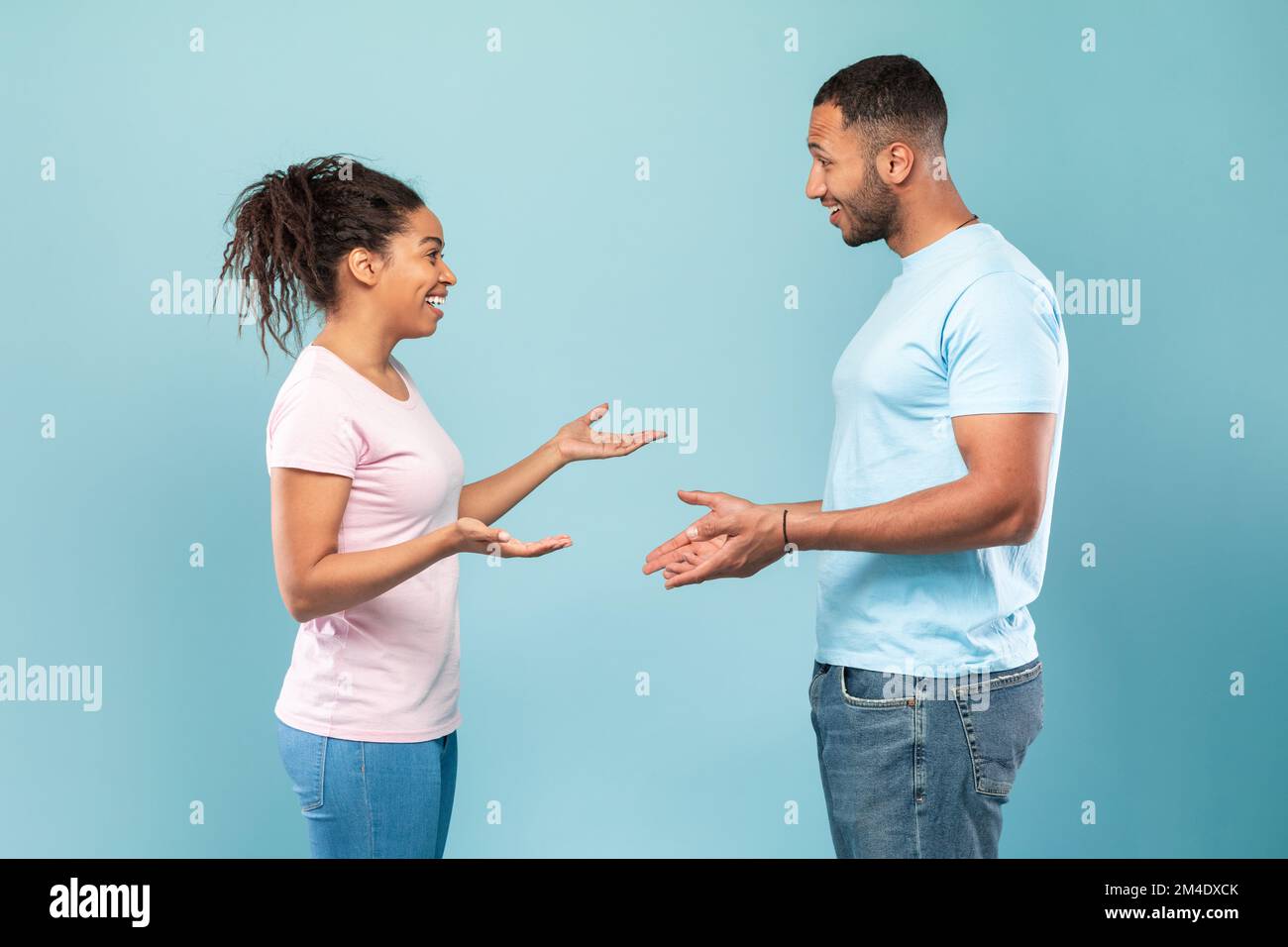 Comunicazione. Profilo ritratto di donna e uomo nero parlando e gesturing su sfondo blu studio Foto Stock