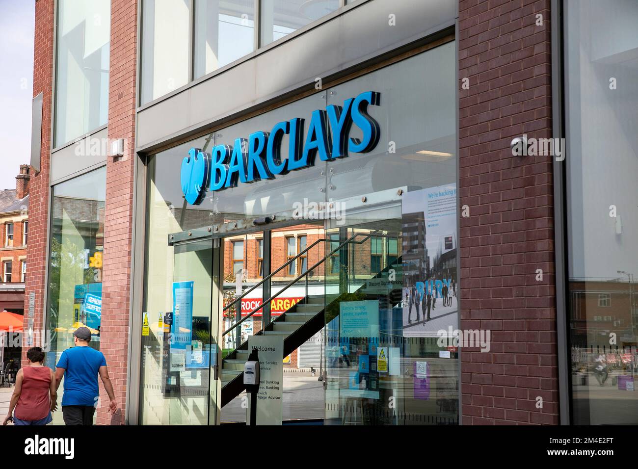 Barclays Bank filiale nel centro di Bury, Greater Manchester, Regno Unito, estate 2022 due persone a piedi passato Foto Stock