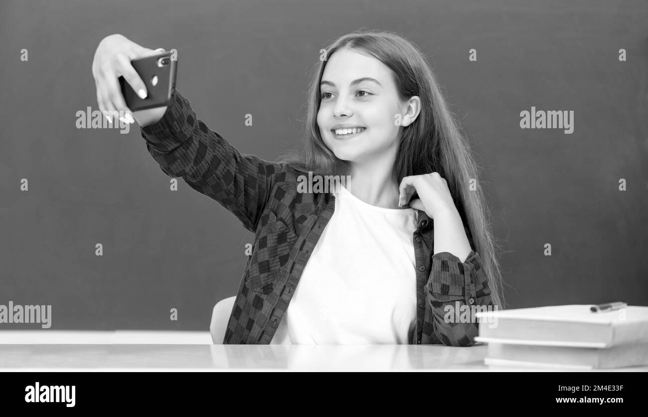 felice bambino che fa selfie su smartphone in classe a lavagna, ritratto Foto Stock