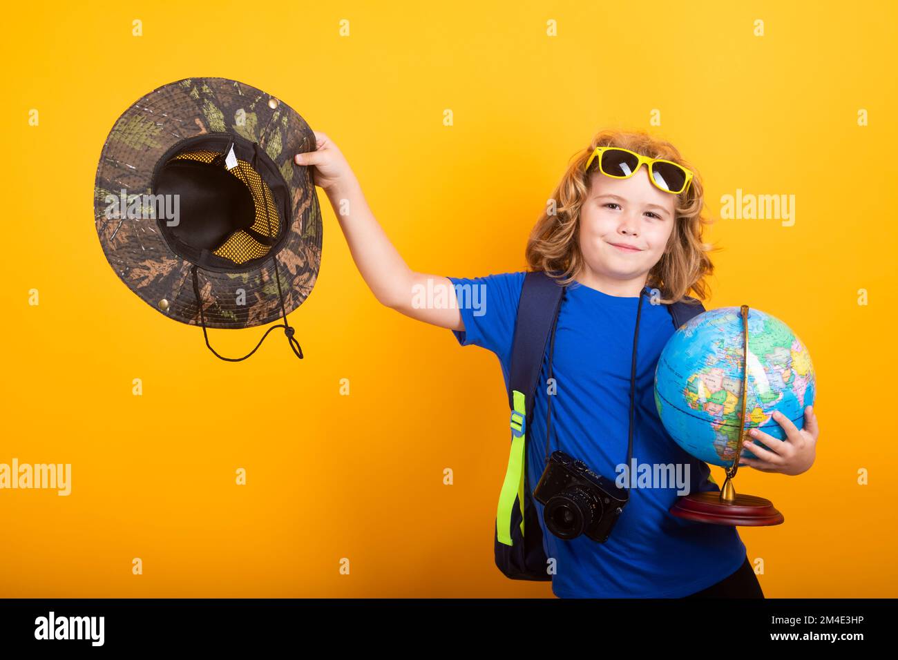 Bambino con pianeta terra modello trekking in natura. Piccolo esploratore. Bambino turistico su sfondo giallo. Foto Stock