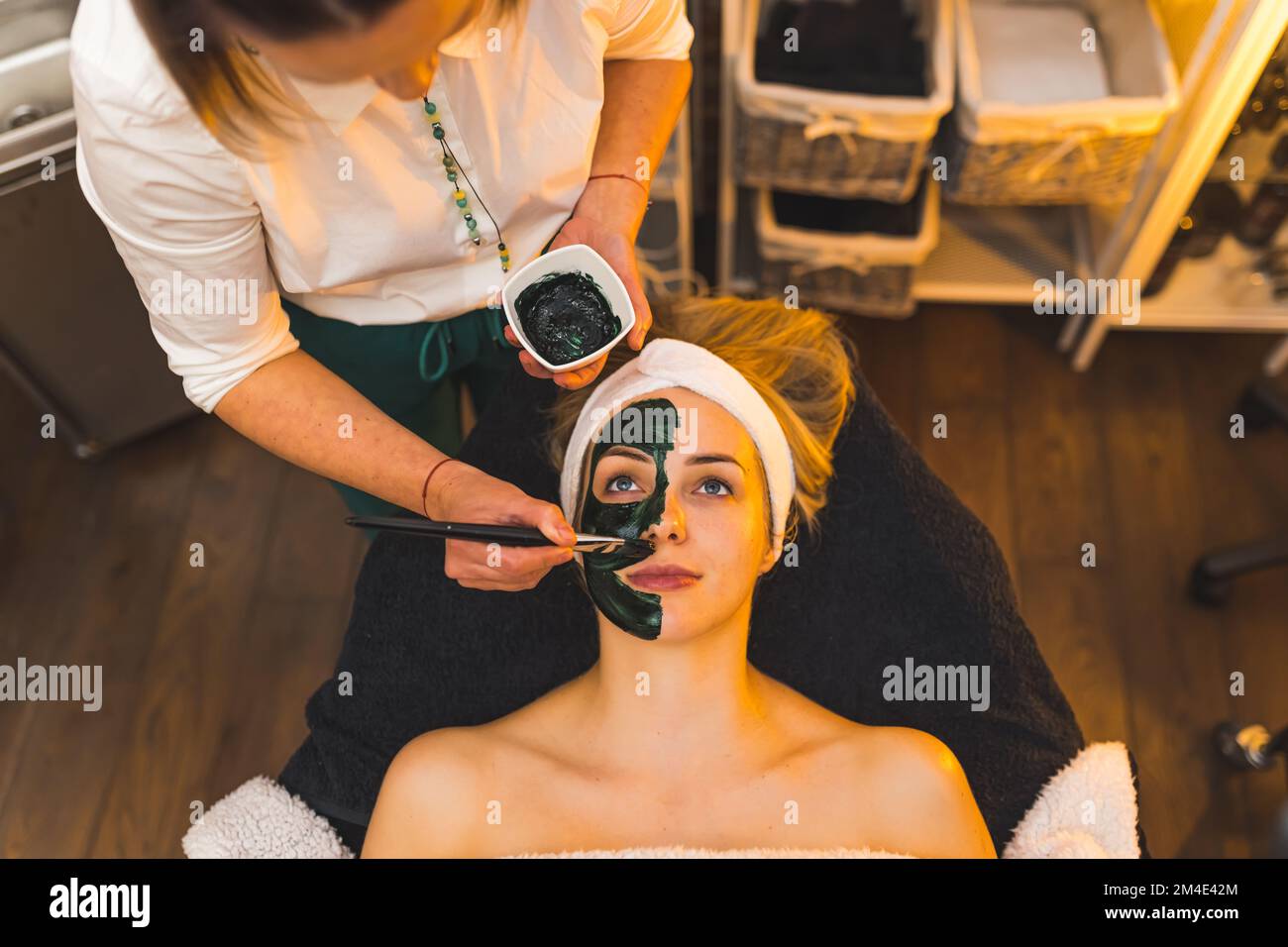 Estetista che applica la maschera facciale su un volto di una donna. Foto di alta qualità Foto Stock