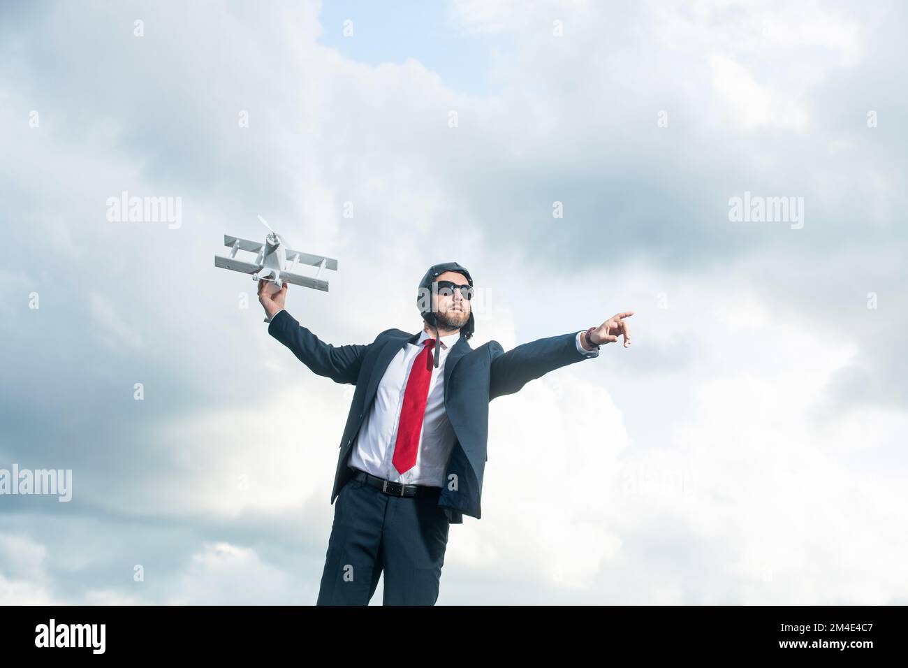 uomo d'affari in tuta e cappello pilota lancio aereo giocattolo su sfondo cielo. concetto aziendale Foto Stock
