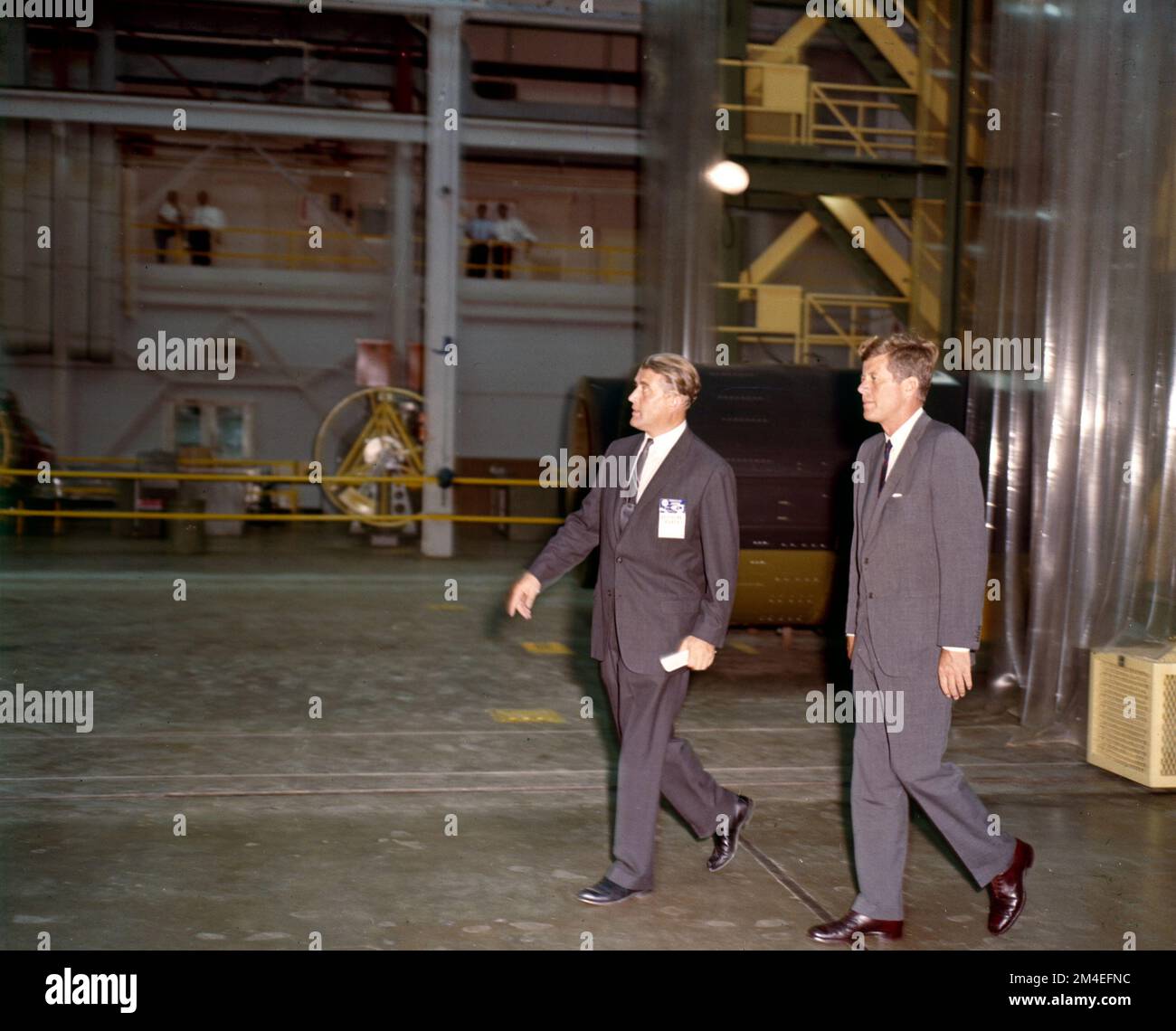 Il presidente John F Kennedy e Werner von Braun camminano insieme in un laboratorio di ricerca di esplorazione spaziale durante la corsa spaziale. Foto Stock