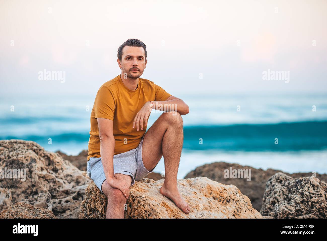 Giovane uomo rilassante sulla spiaggia al tramonto Foto Stock