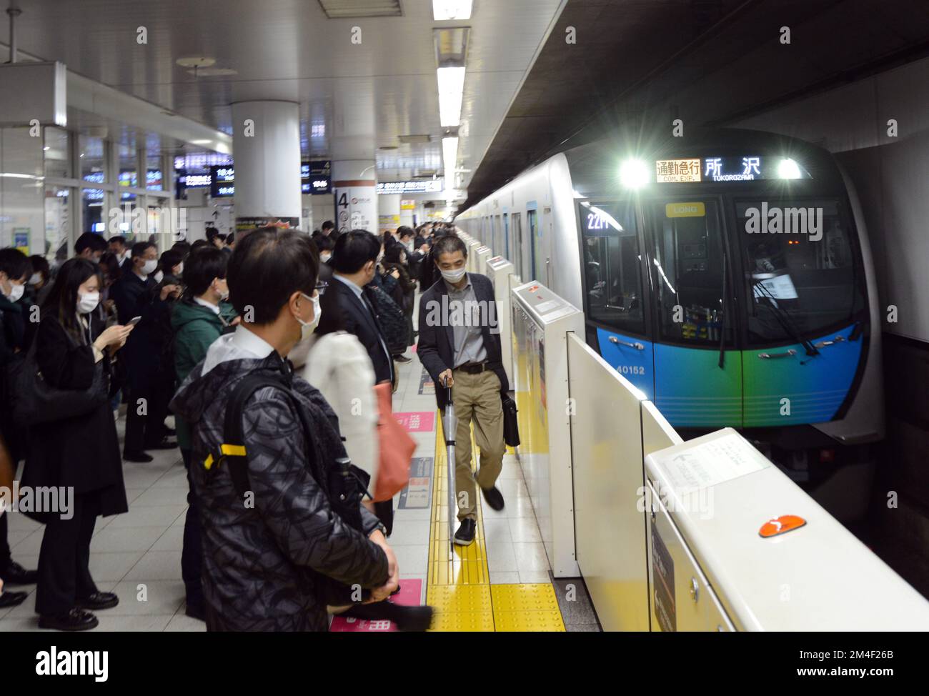 Passeggeri giapponesi in attesa di salire a bordo del treno della metropolitana a Tokyo, Giappone. Foto Stock