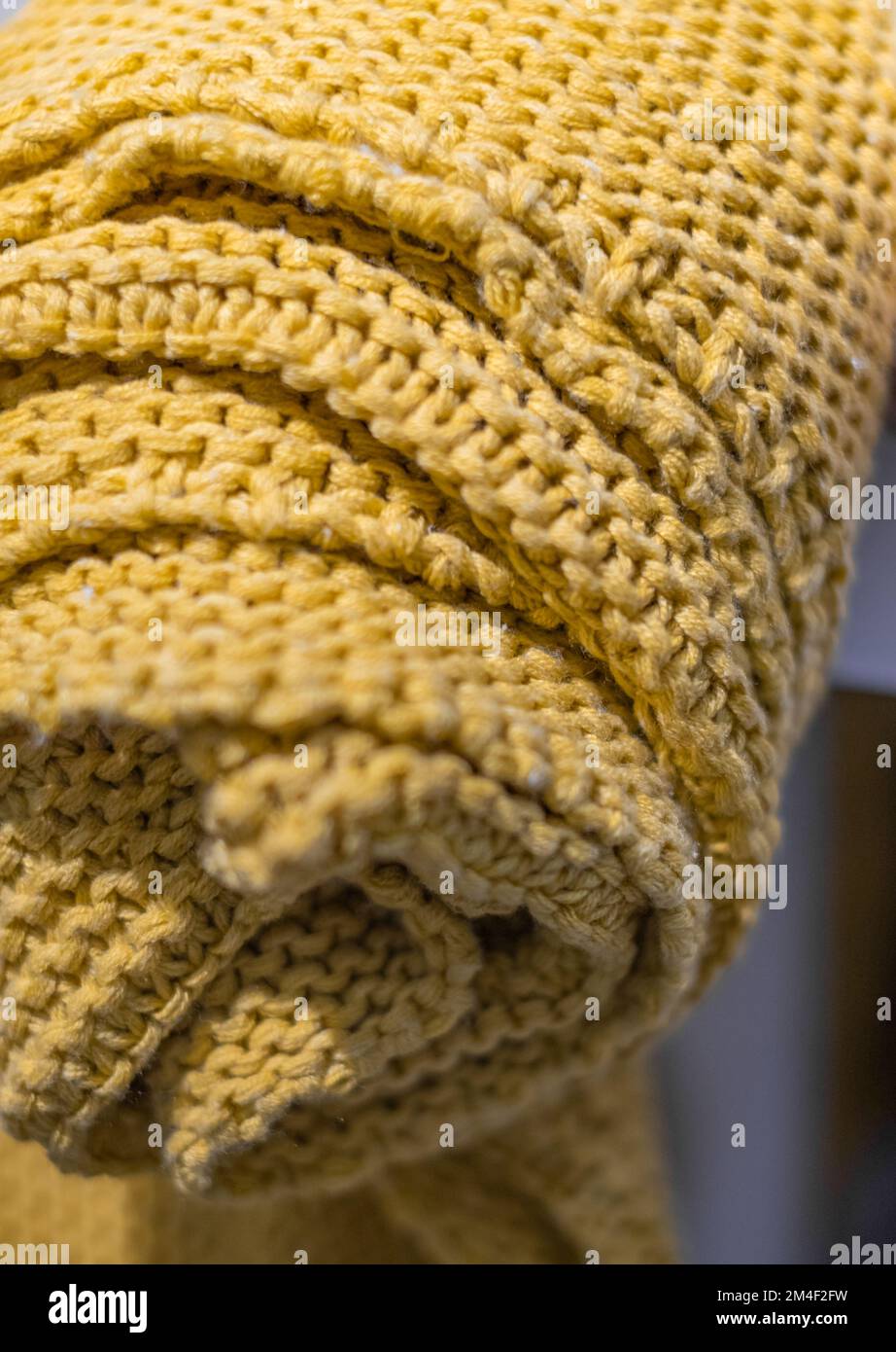 Copriletto in maglia beige giallo chunky. Coperta in lana merino lavorata a mano in interni eleganti e accoglienti. Tessuto lavorato a maglia di lana Foto Stock
