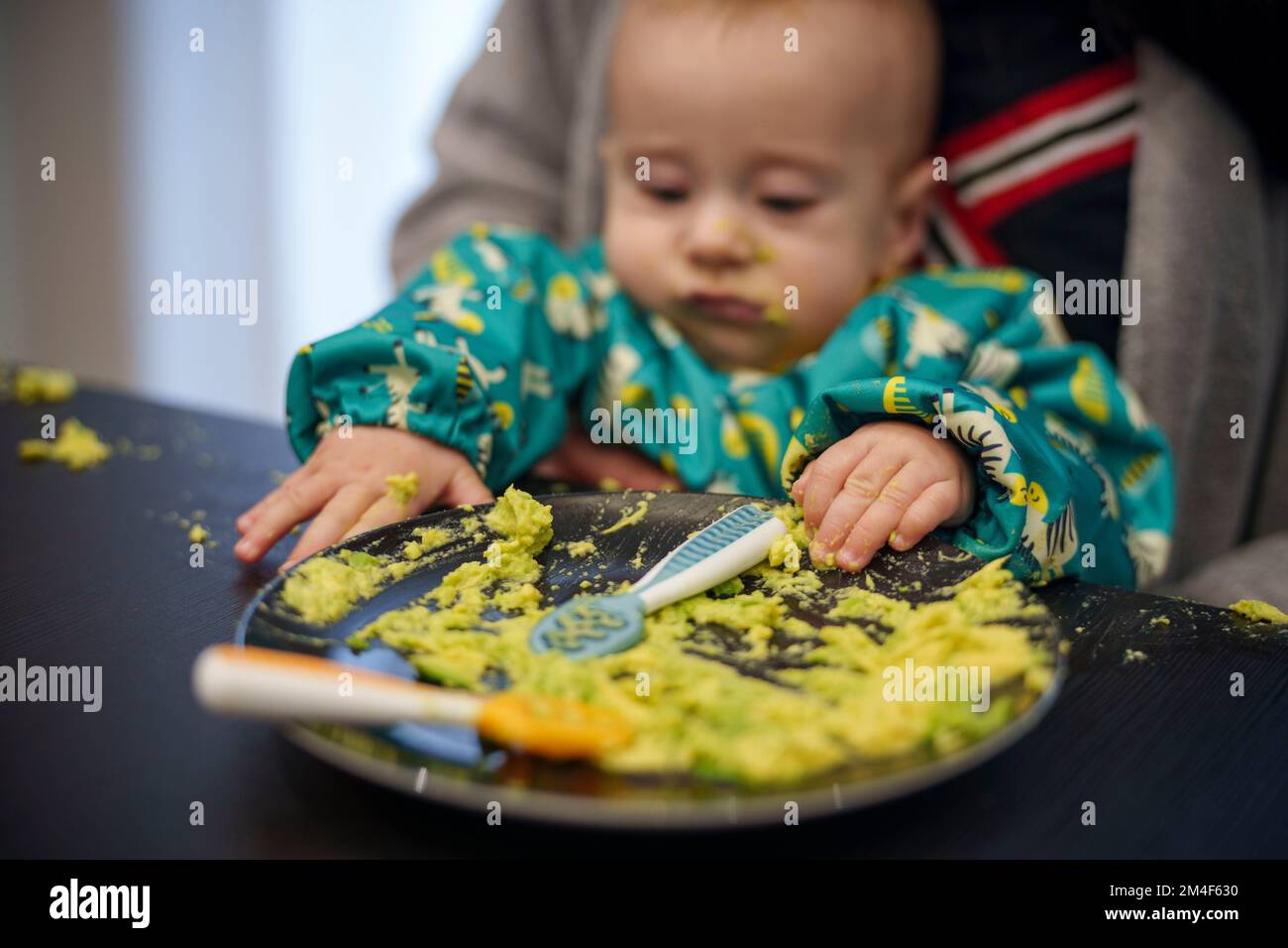 Il bambino che fa un pasticcio mentre mangia Foto Stock