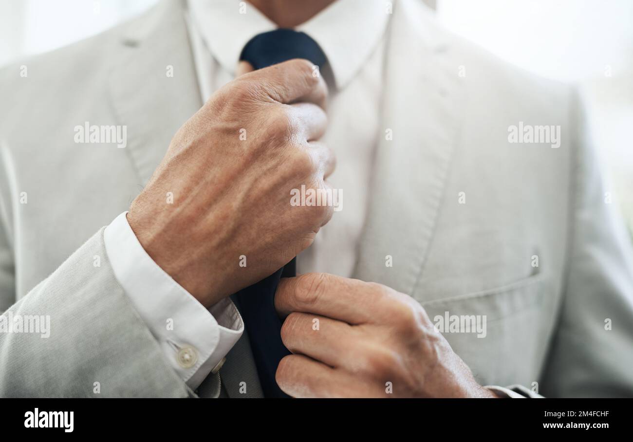 Il tocco finale. un uomo d'affari irriconoscibile che indossa un vestito di affari mentre regola il suo cravatta prima di uscire per lavorare a casa durante il giorno. Foto Stock