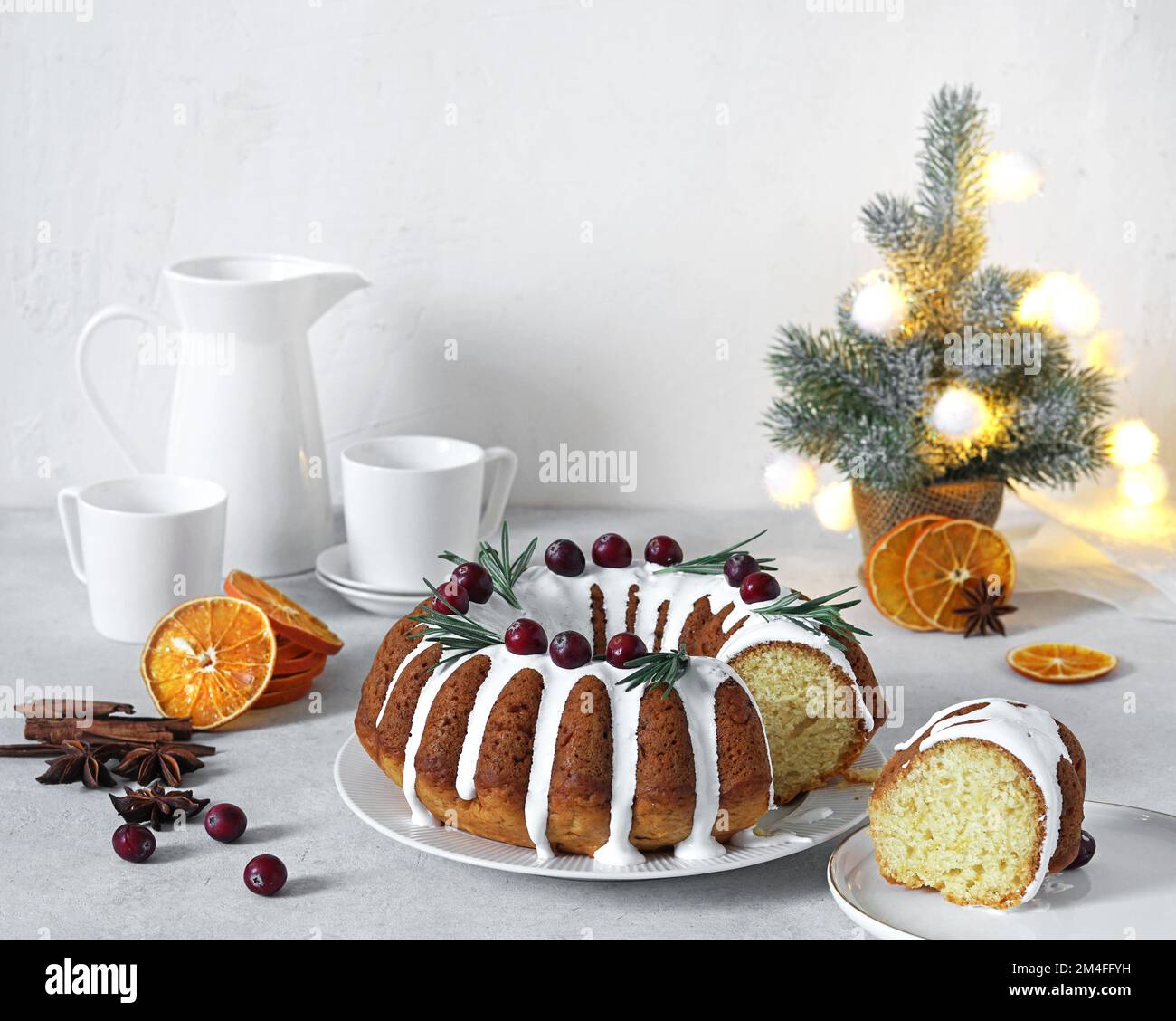 Torta di Natale, budino su piatto bianco con arance secche e tazze di caffè sullo sfondo. Spazio di copia. Foto Stock