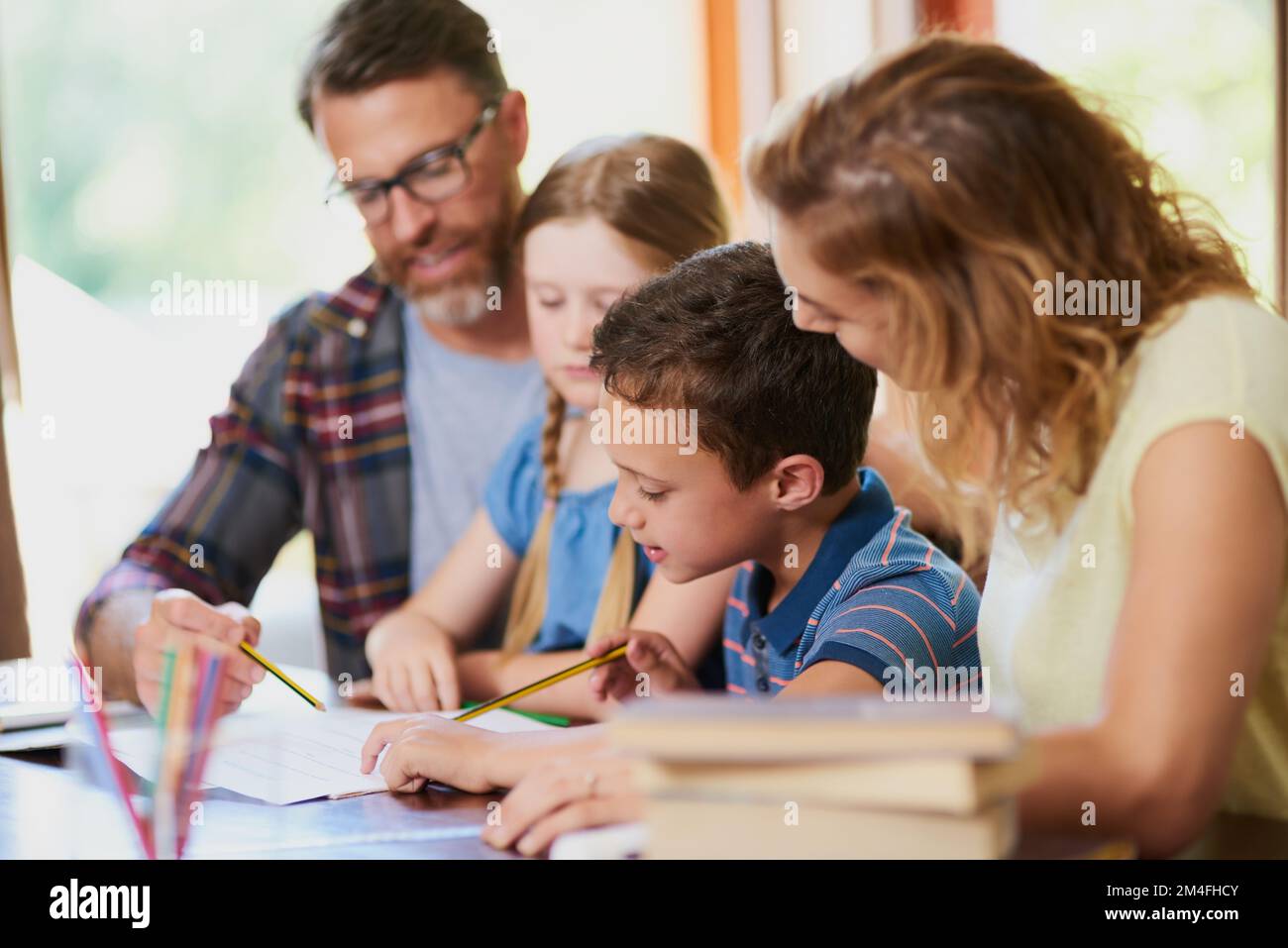 Lavorare insieme ai compiti a casa. due genitori aiutano i loro figli adorabili con il lavoro scolastico a casa. Foto Stock