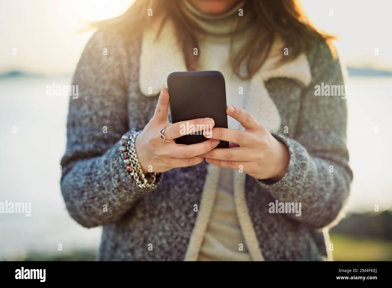 Aggiornamento dello stato dell'oceano. una giovane donna irriconoscibile che usa il cellulare mentre fuori dall'oceano. Foto Stock