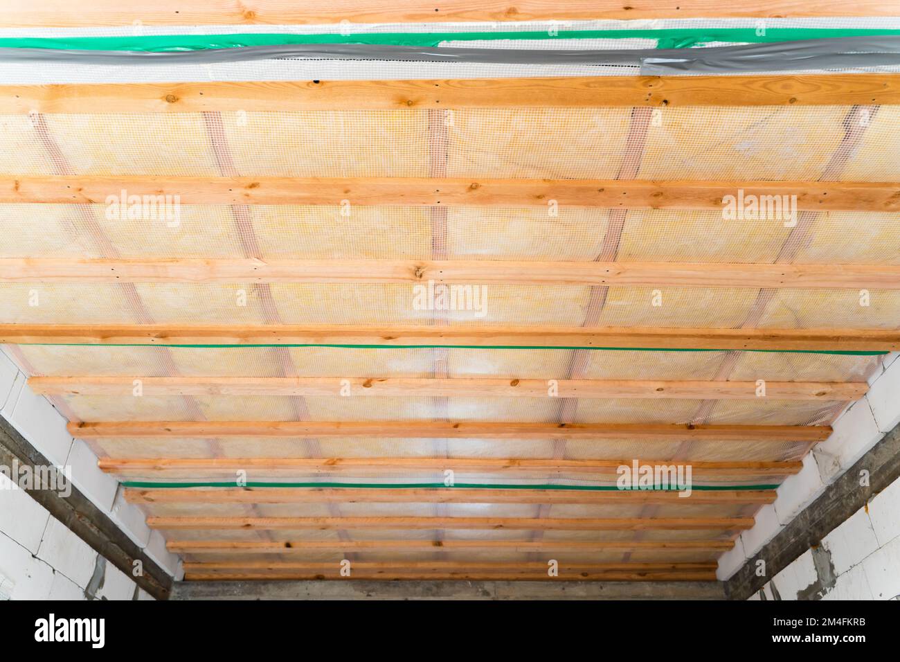 Soffitto isolato di una casa privata con una cassa di legno. Il tetto è isolato con lana di vetro e rivestito con una barriera al vapore, vista dal basso Foto Stock