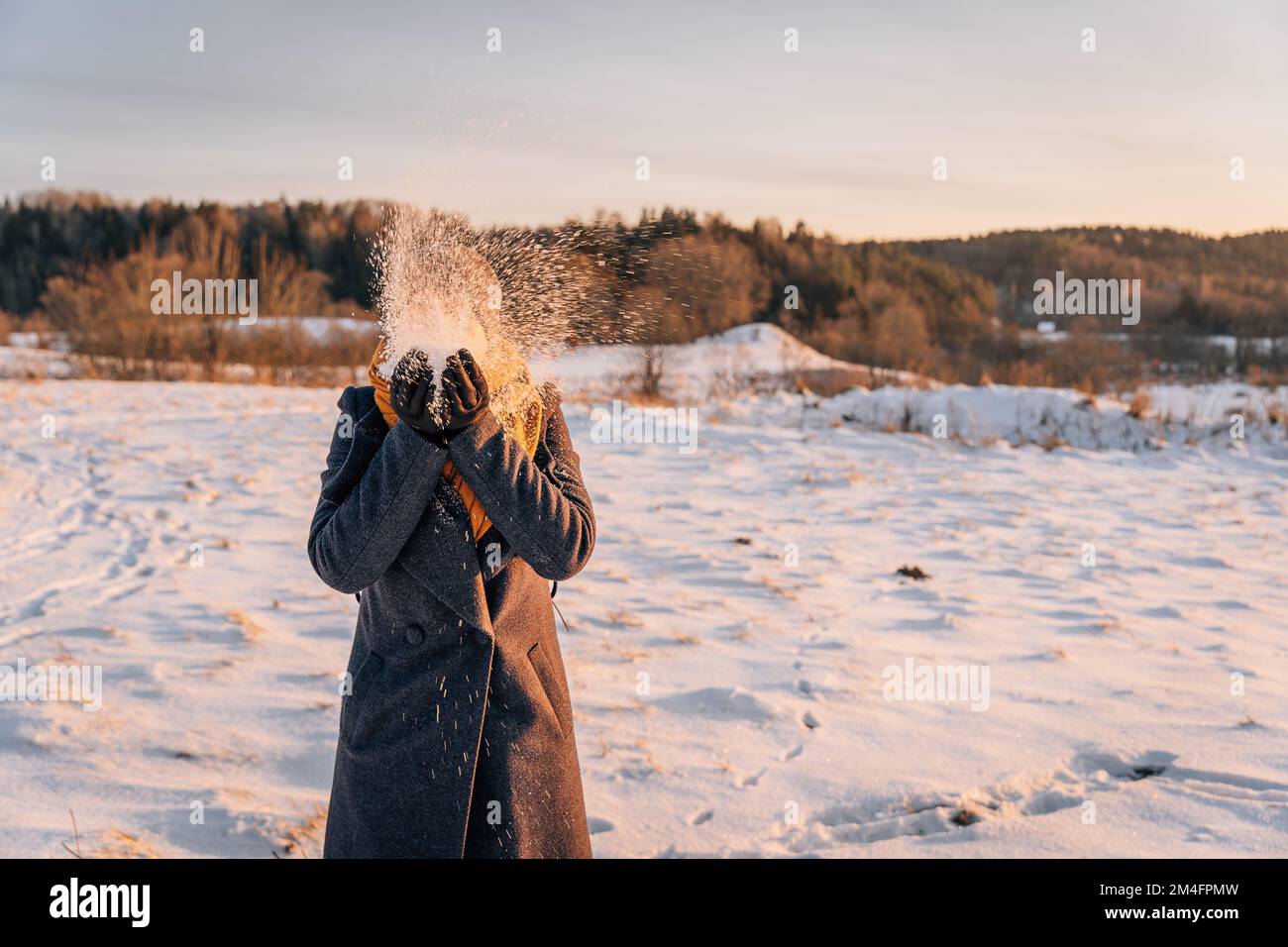Ritratto invernale senza volto di una donna che lancia la neve Foto Stock