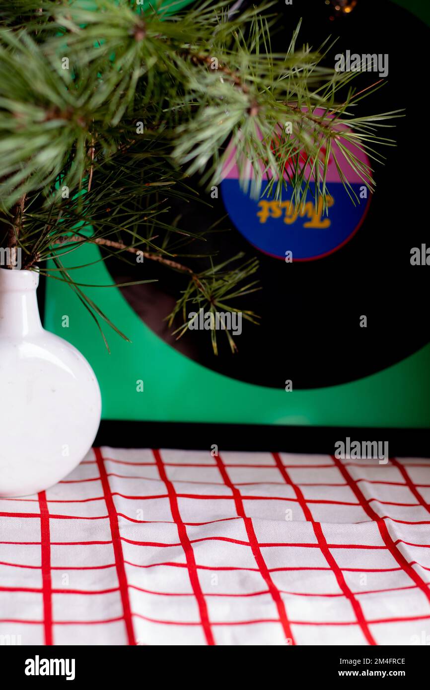 tovaglia bianca e rossa sulla tavola, su di essa si trova un vaso bianco con un ramo di abeti Foto Stock