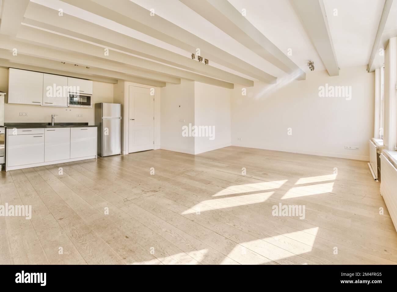 un soggiorno vuoto con pavimento in legno e elettrodomestici bianchi sulla parete al centro della stanza Foto Stock