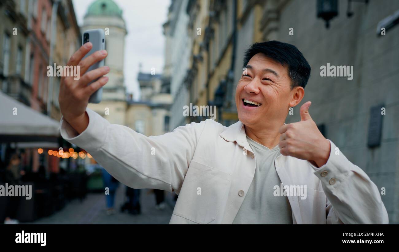 Gioioso adulto maschio in possesso di smartphone guardando lo schermo scattare foto sulla webcam felice uomo blogger posa per la fotografia utilizzando il telefono per Foto Stock