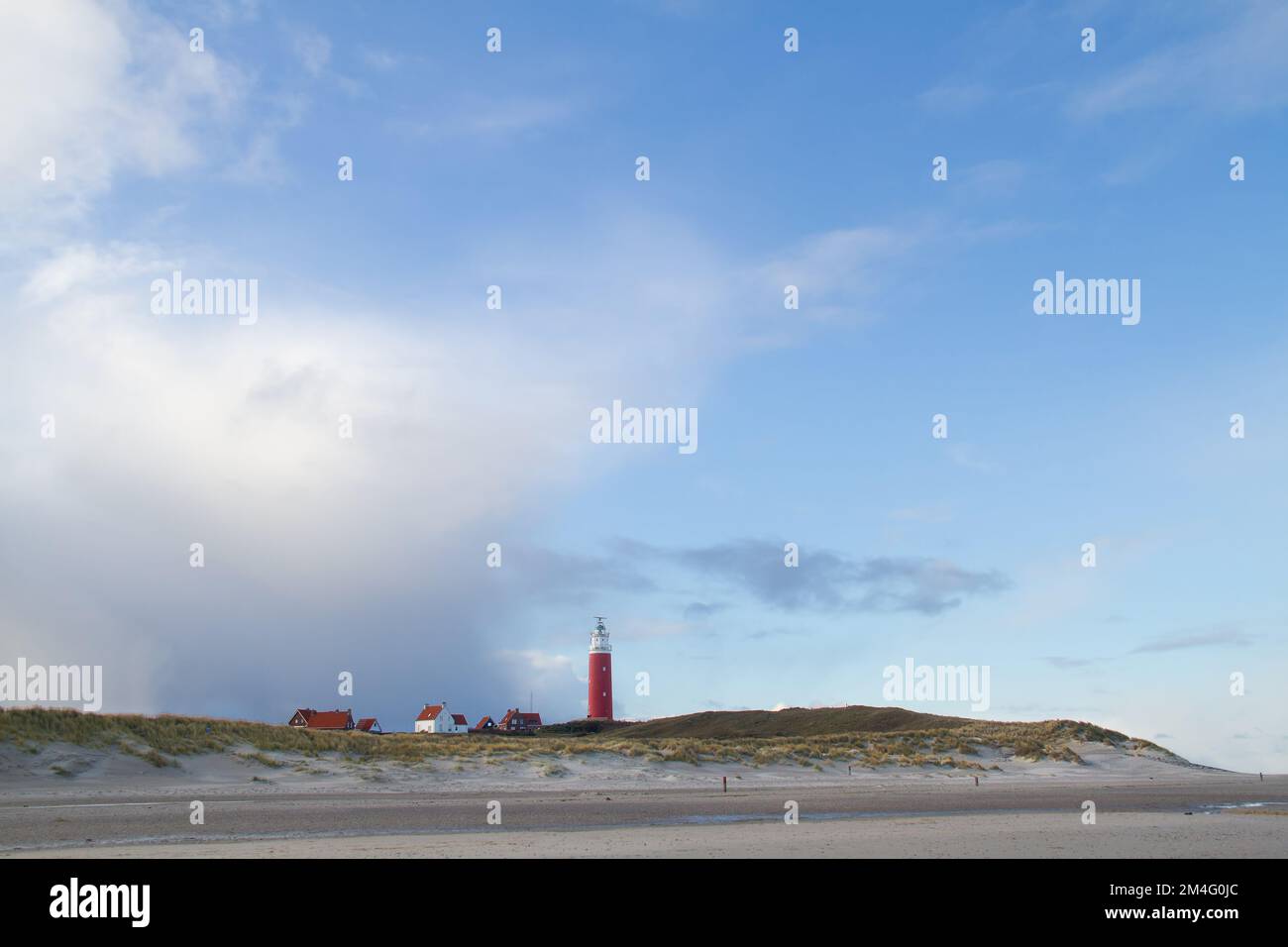 Il faro Eierland e alcune case bianche con tetti di tegole leggere nelle dune dell'isola olandese Texel nel mare di Wadden Foto Stock
