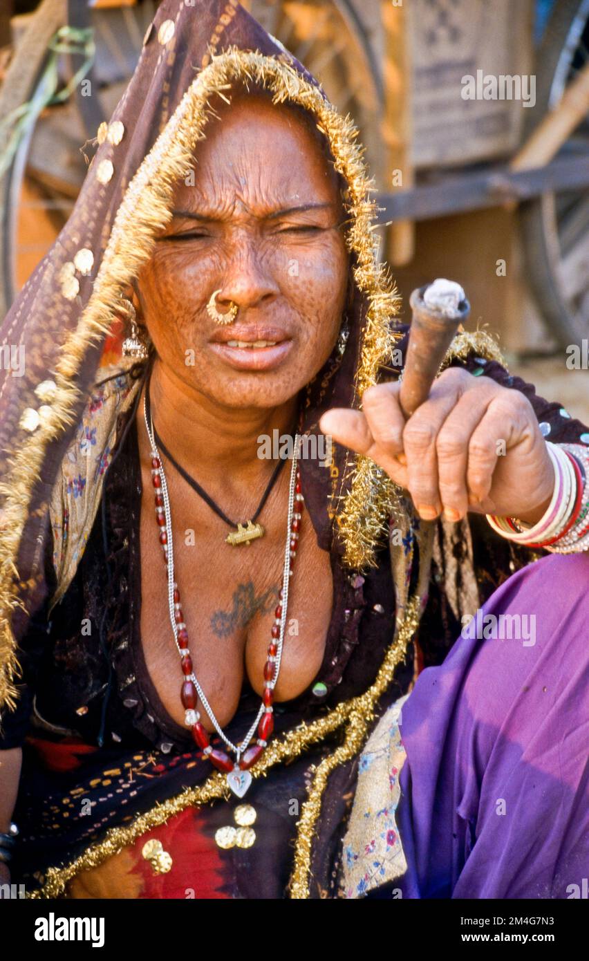 Signora locale che fuma marihuana durante la fiera del cammello di Pushkar, uno dei più grandi mercati di cammelli in Asia. Foto Stock