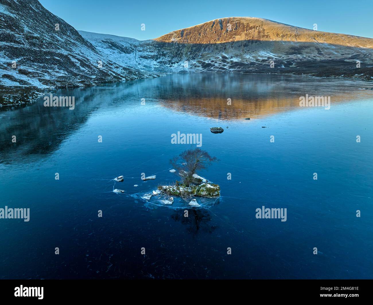 Ripresa aerea di Loch Skeen nella Riserva Naturale della coda di Grey Mare in un'ora d'oro in un giorno gelido di dicembre. Foto Stock