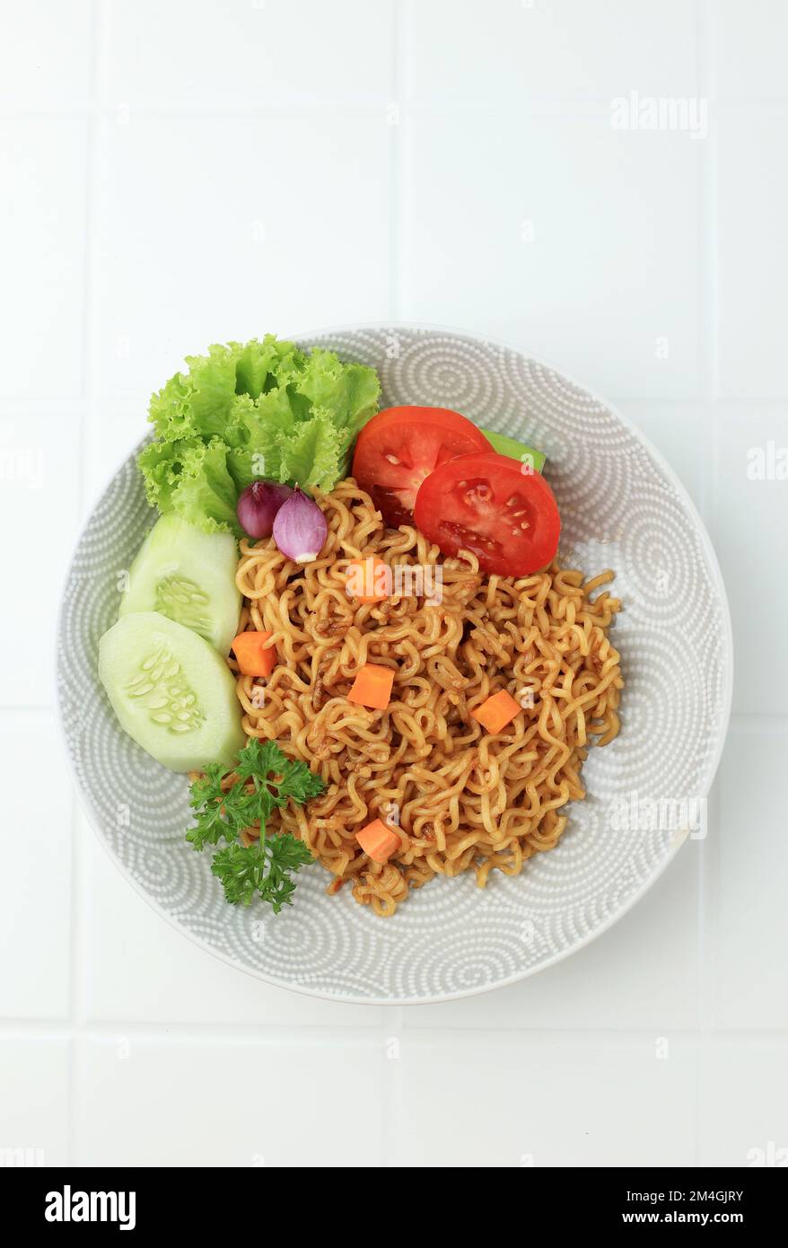 Fried Noodle Indomie Goreng, indonesiano popolare Instant Noodle. Servito con cetriolo e pomodoro. Vista dall'alto Foto Stock