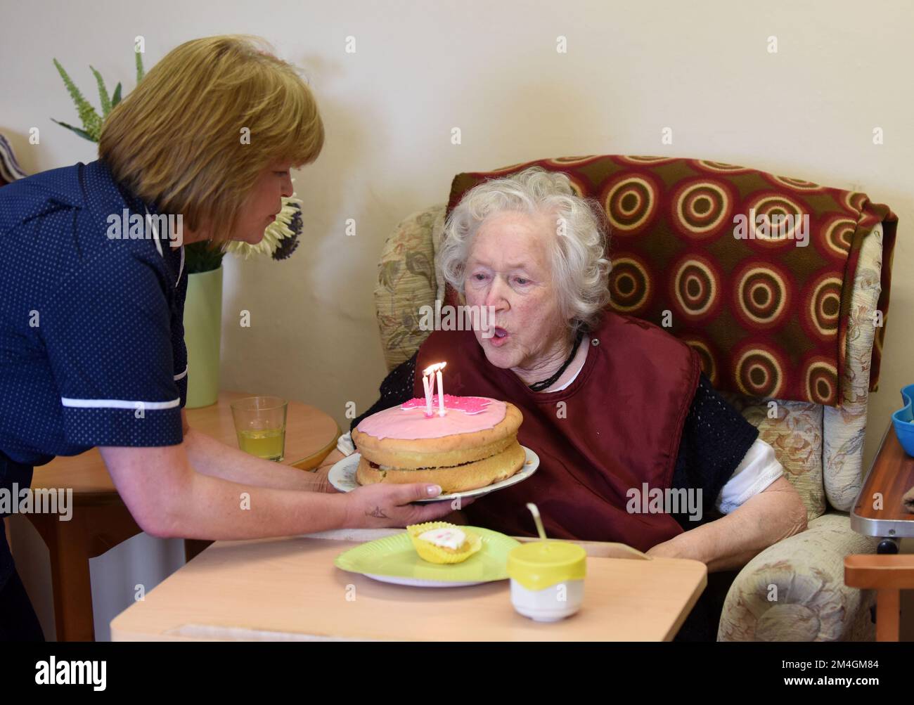 Care Home residente celebrare un altro compleanno come lei soffia le candele sulla torta di compleanno Gran Bretagna 2016 Foto Stock
