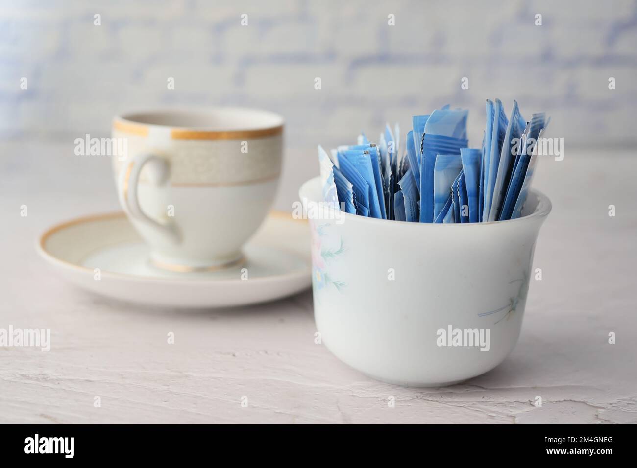 Dolcificante sostitutivo dello zucchero in una confezione e una tazza di tè sul tavolo Foto Stock