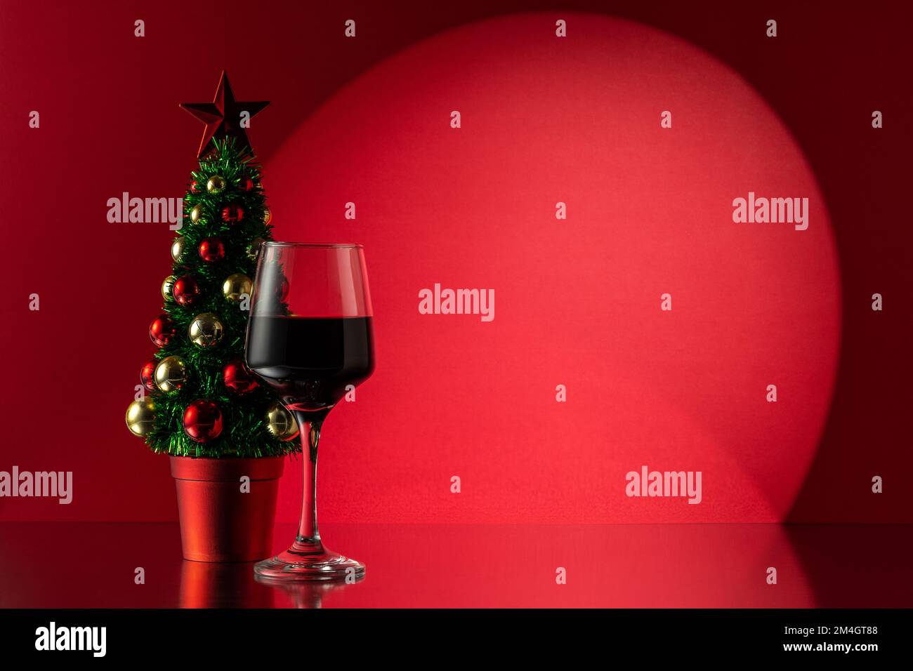 Albero di Natale con bicchiere di vino rosso. Capodanno o sfondo di Natale. Foto Stock