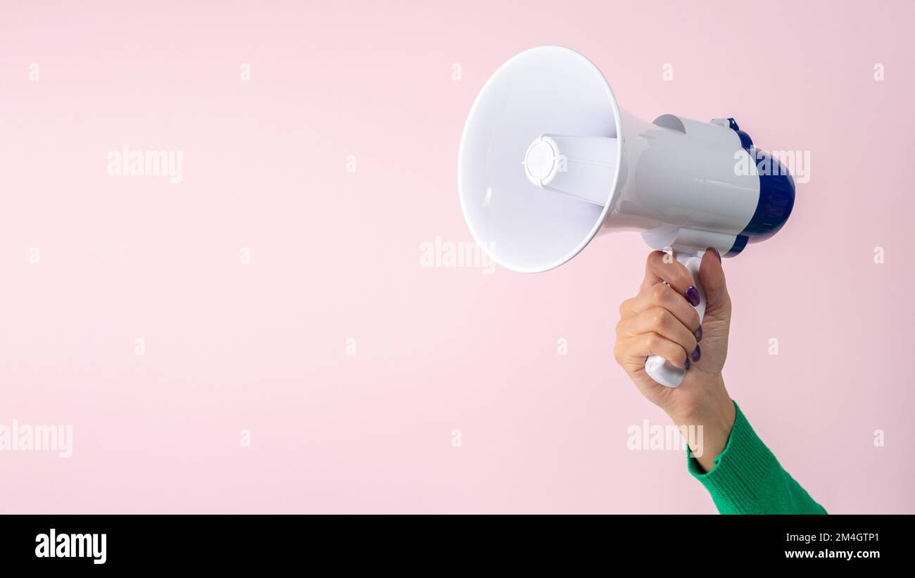 Mano donna con megafono su sfondo rosa. Concetto di annuncio creativo. Foto Stock