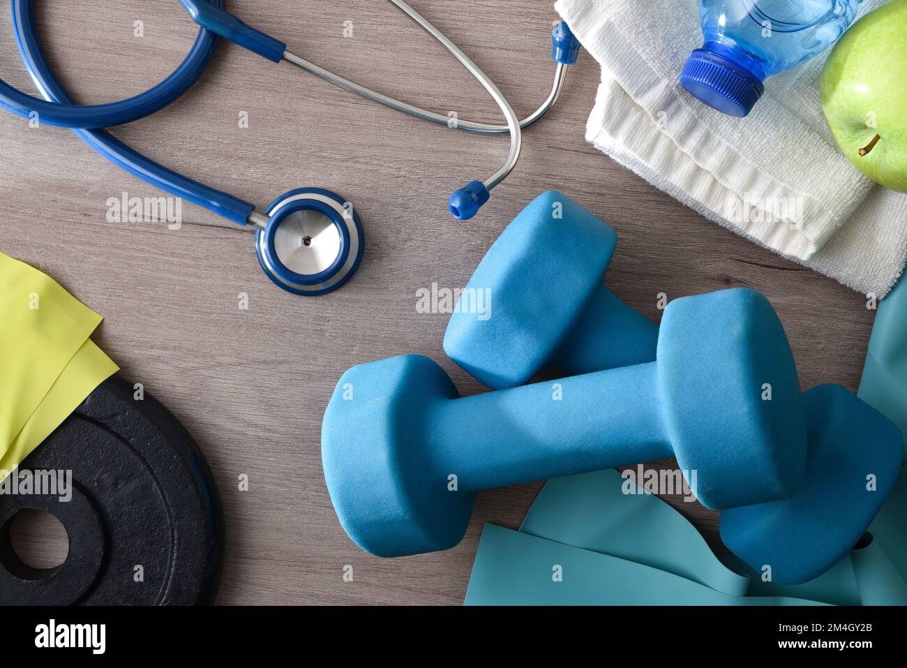 Concetto di sport e salute con attrezzatura sportiva su tavolo in legno con stetoscopio mela e acqua. Vista dall'alto. Foto Stock