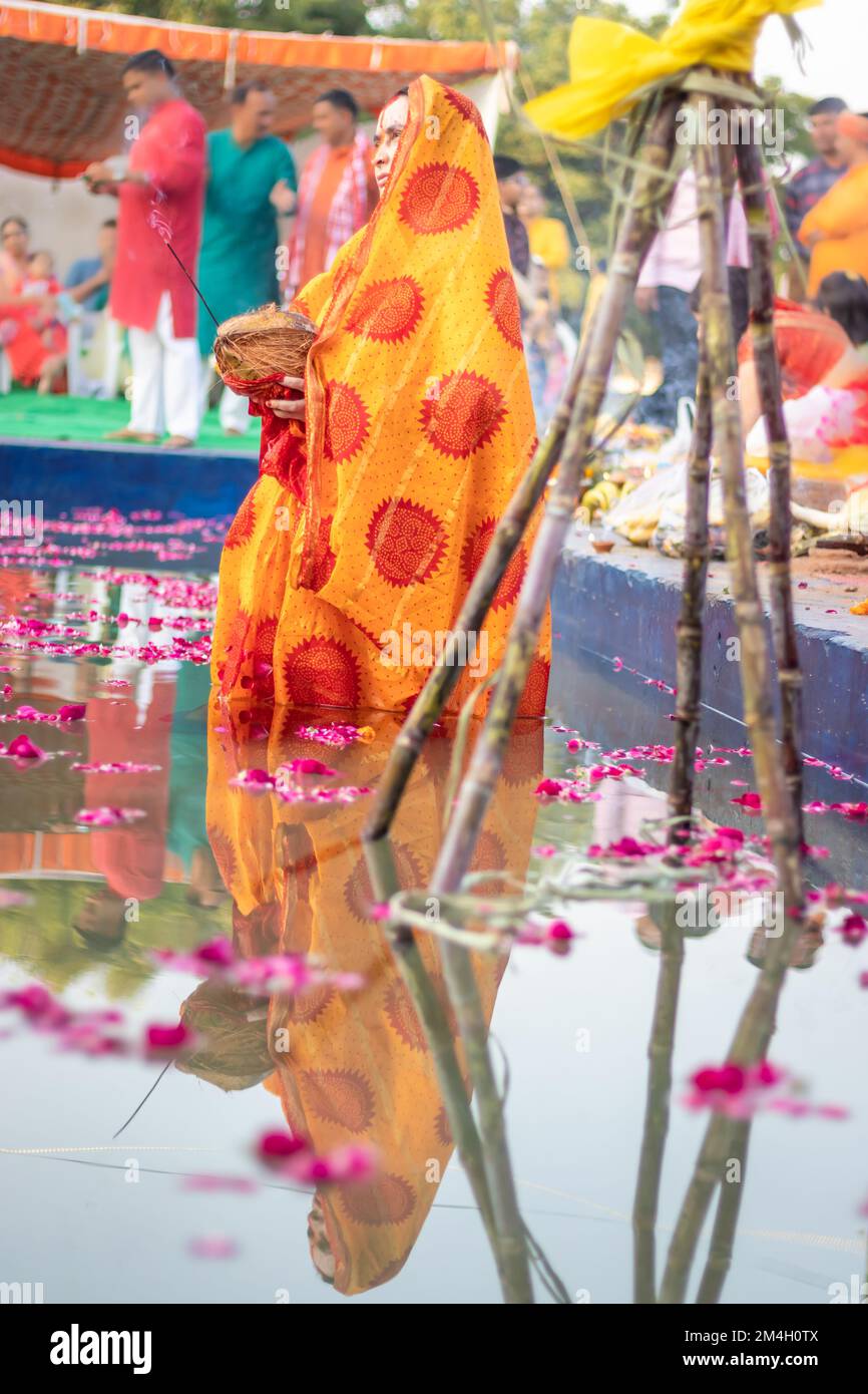 Donna devota con offerte religiose per Dio sole durante la festa Chhath da un angolo piatto Foto Stock