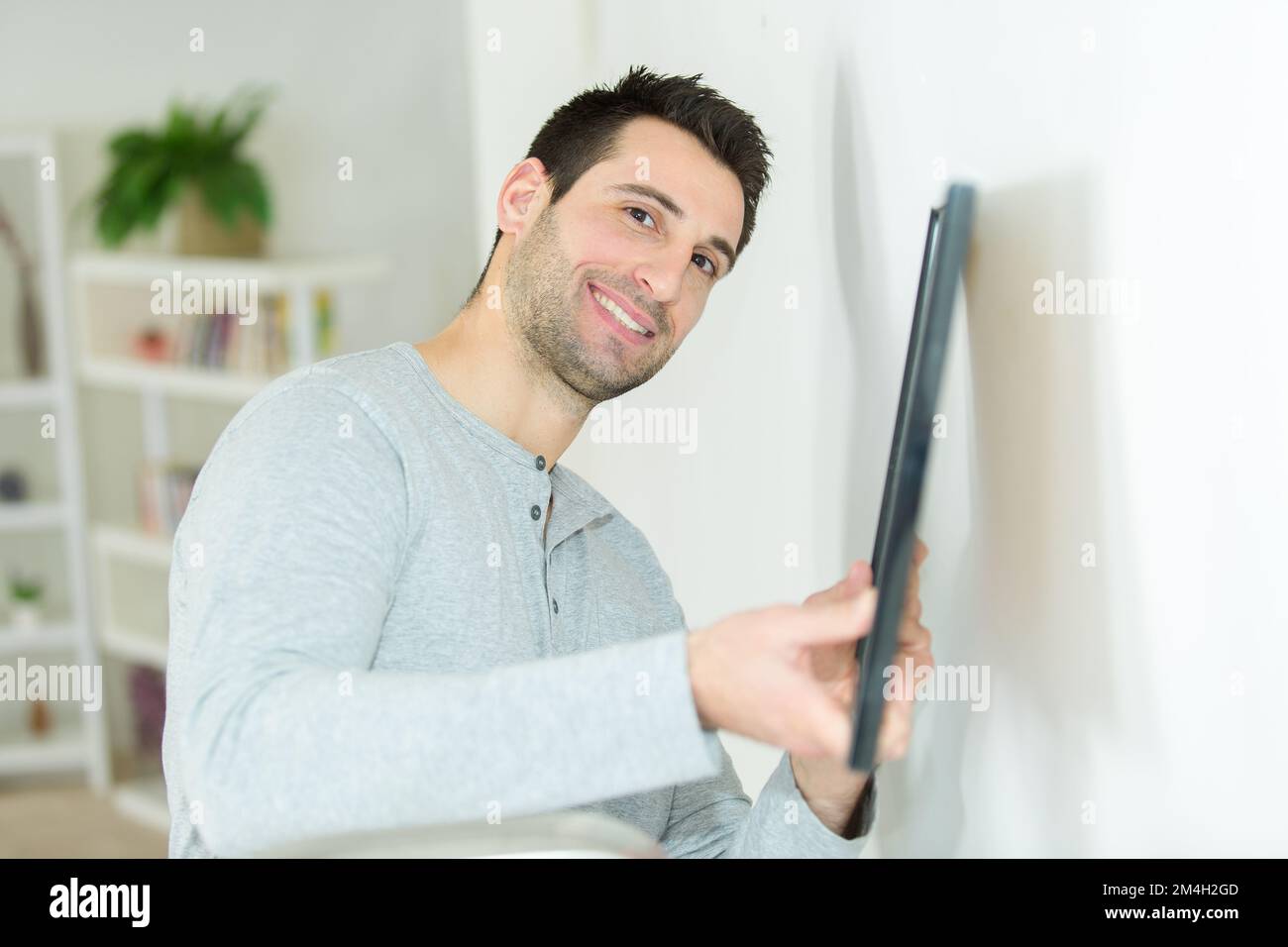 Uomo di mettere cornice immagine sulla parete Foto Stock