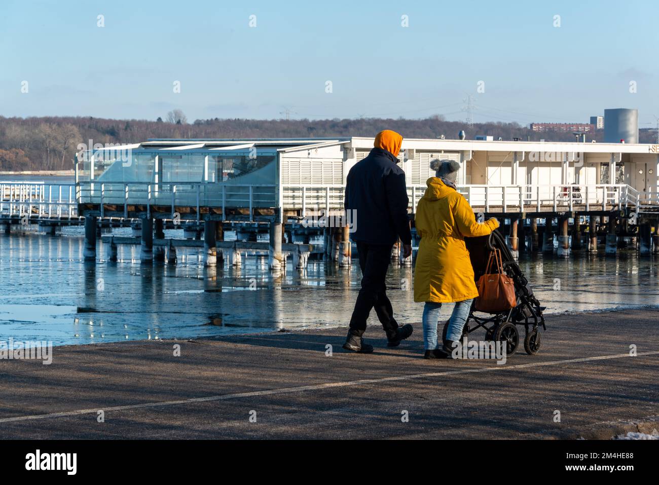 Gefrorenes Wasser an der Kieler Förde bei der Seebadeanstalt Düsterbrook ein Paar mit Kinderwagen geht vorbei Foto Stock