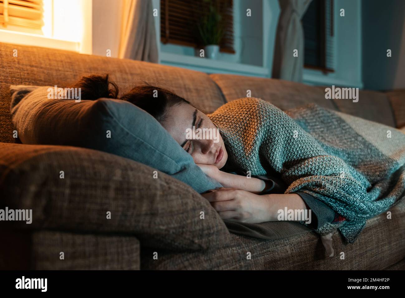 Influenza e disperazione. Malattia giovane donna caucasica si trova sul  divano coperto di coperta e guardare la tv. Vista ravvicinata. Concetto di  problema psicologico e di Lon Foto stock - Alamy