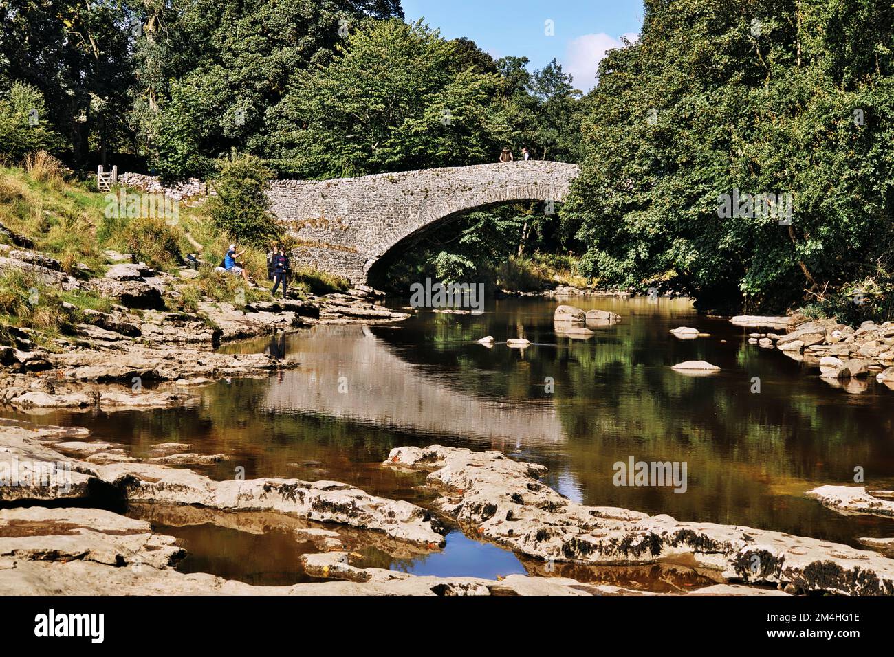 Ribble Valley, Yorkshire Dales, North Yorkshire, Inghilterra, Regno Unito - scena tranquilla, la gente che gode Stainforth Bridge riflesso nel fiume Ribble Foto Stock